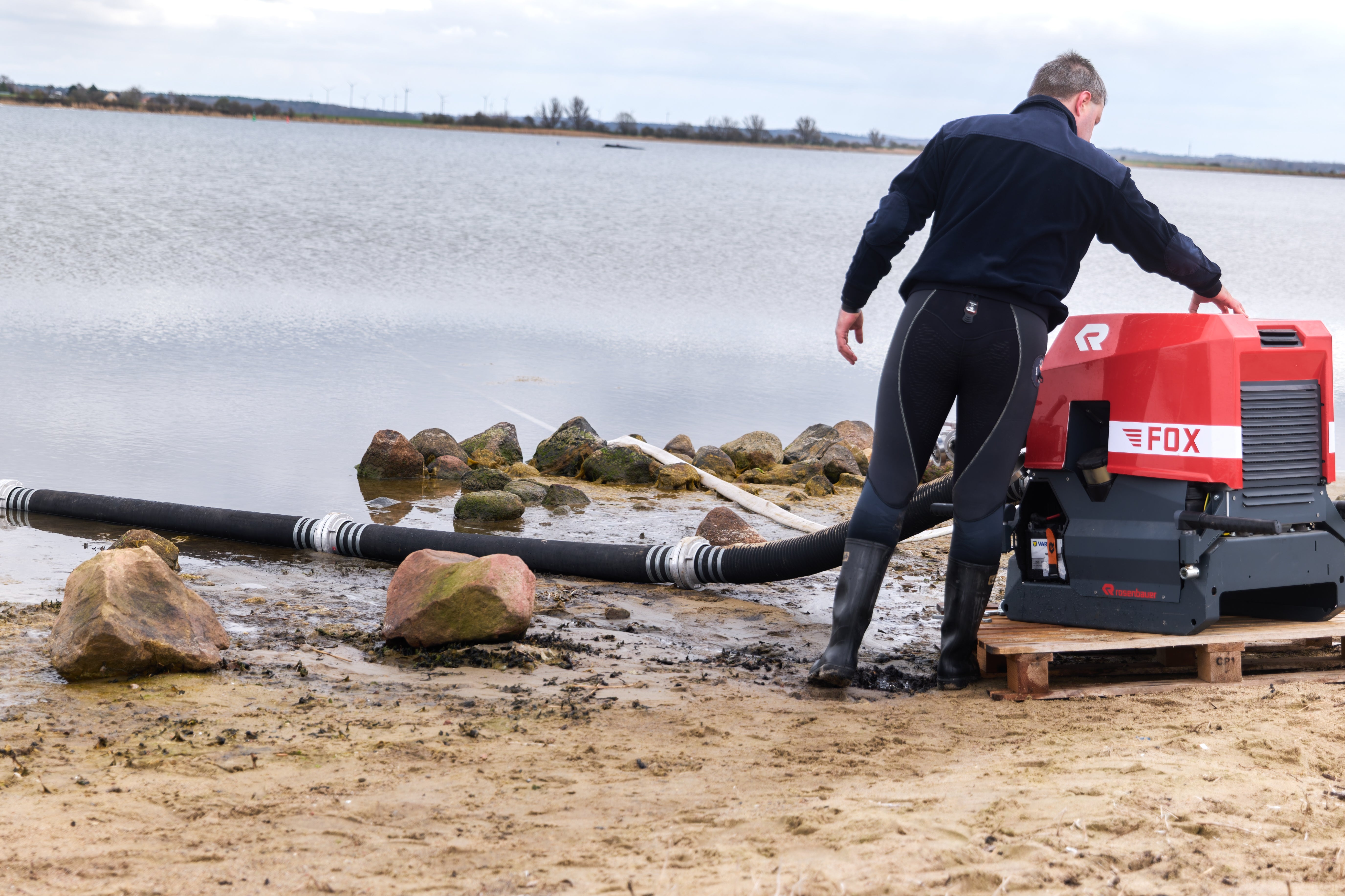03.04.2026, Mecklenburg-Vorpommern, Weitendorf-Hof: Einsatzkr&auml;fte der Feuerwehr benetzen den R&uuml;cken des Wals, der aus dem Wasser ragt (Hintergrund). (Marcus Golejewski/dpa)
