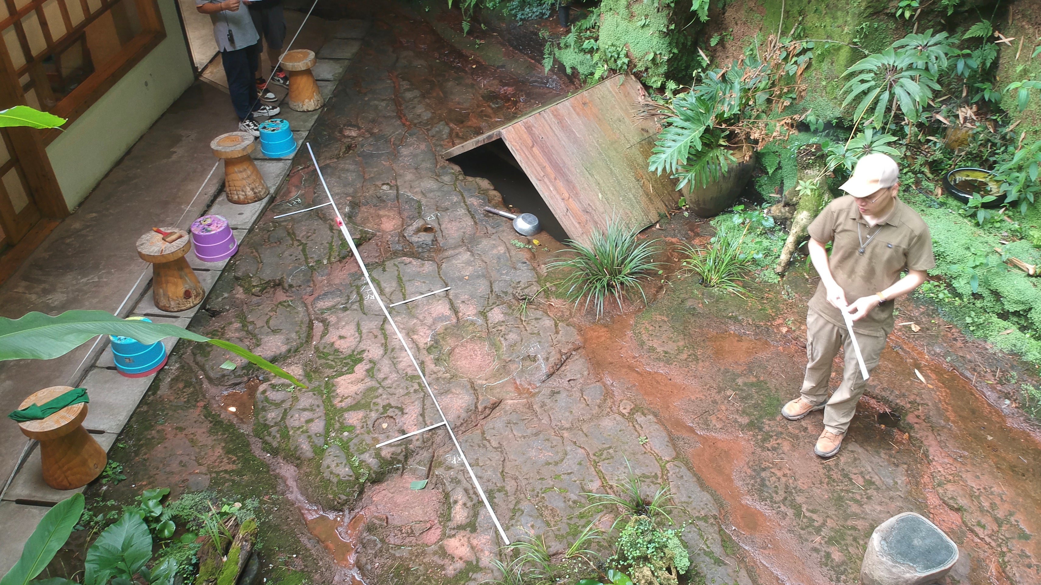 HANDOUT - 16.07.2022, China, Leshan: Ein Wissenschaftler im Forscherteam von Lida Xing untersucht die etwa 100 Millionen Jahre alte Dinosaurier-Fu&szlig;abdr&uuml;cke. Wie die staatliche Nachrichtenagentur Xinhua berichtete, waren dem Dinosaurier-Enthusiasten Ou Hongtao auff&auml;llige Bodenvertiefungen im Garten des Restaurants in der Stadt Leshan ins Auge gefallen. Sp&auml;ter best&auml;tigte ein Team professioneller Pal&auml;ontologen die Entdeckung. Demnach handelte es sich um die Abdr&uuml;cke zweier etwa acht Meter langer Sauropoden aus der fr&uuml;hen Kreidezeit. (zu dpa: "Gast findet Dinosaurier-Fu&szlig;abdr&uuml;cke in chinesischem Restaurant ") Foto: ---/Lida Xing Team/dpa - ACHTUNG: Nur zur redaktionellen Verwendung im Zusammenhang mit der aktuellen Berichterstattung und nur mit vollst&auml;ndiger Nennung des vorstehenden Credits +++ dpa-Bildfunk +++

