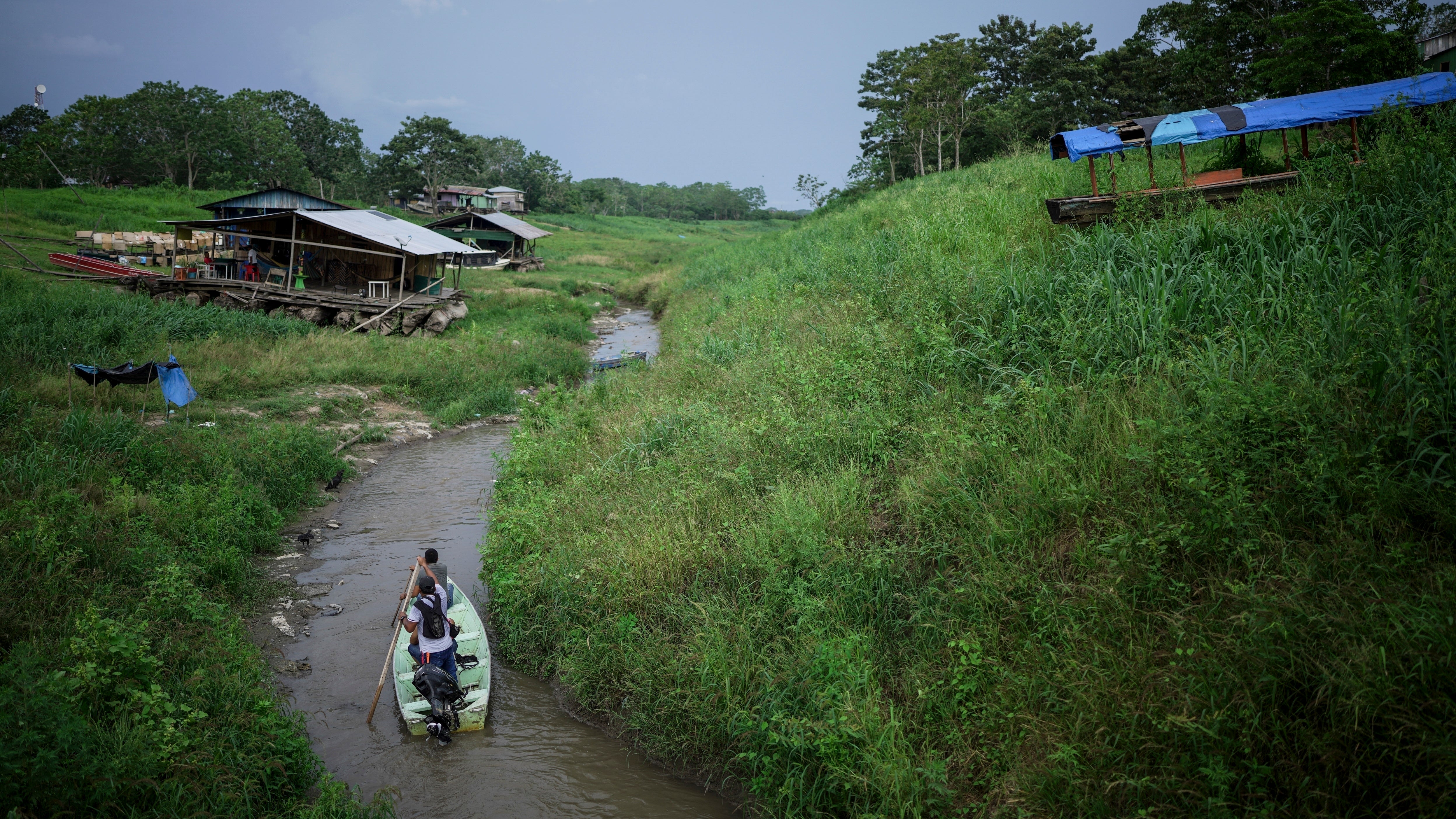 20. Oktober 2024: Menschen man&ouml;vrieren in einem Boot durch den niedrigen Pegel eines Nebenflusses, der mit dem Amazonas verbunden ist. Das Foto wurde auf der Isla de la Fantasia am Rande von Leticia, Kolumbien aufgenommen.  (AP Photo/Ivan Valencia)