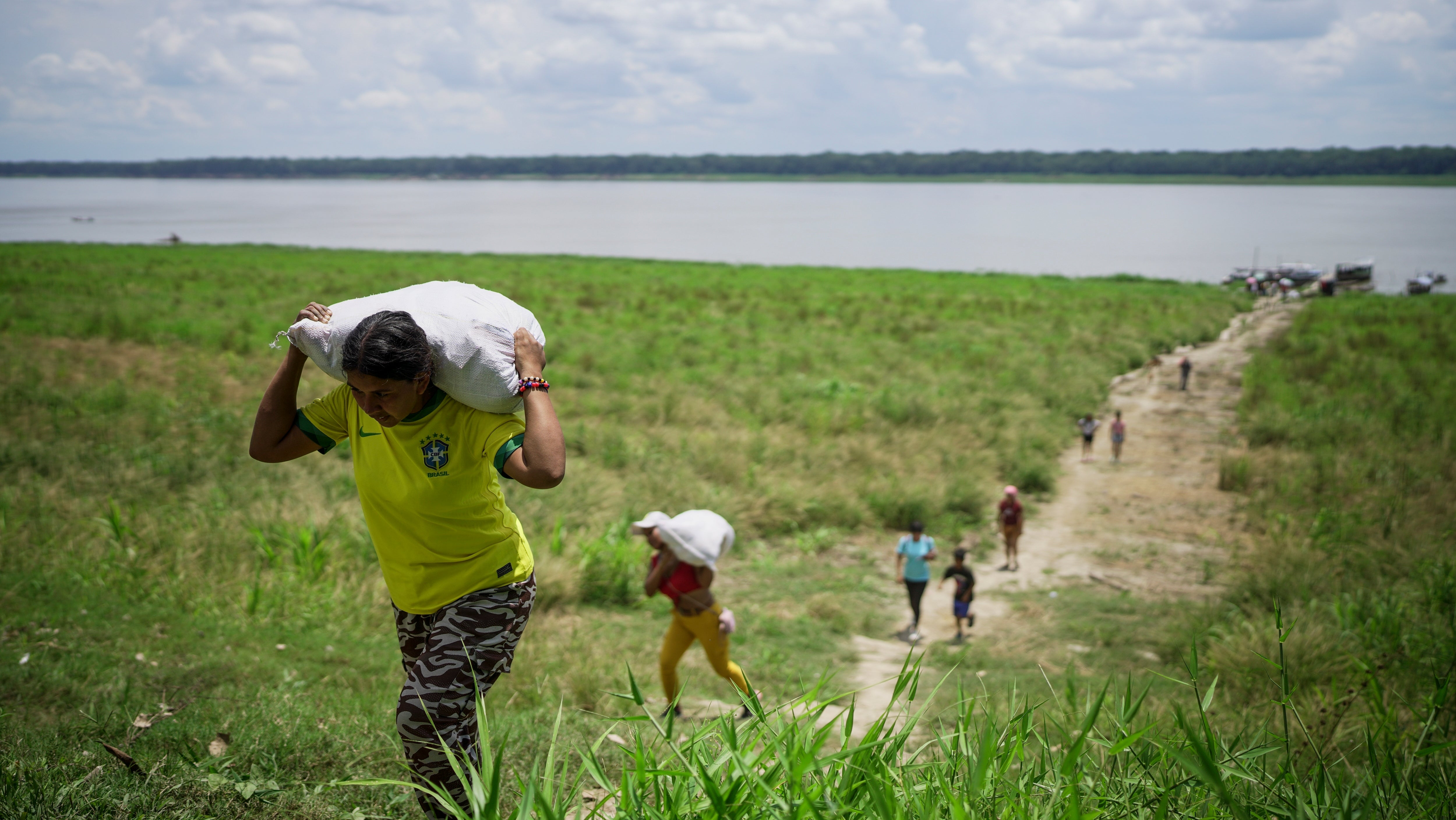 20. Oktober 2024, Loma Linda, nahe Leticia, Kolumbien: Angeh&ouml;rige der indigenen Gemeinschaft der Tikuna tragen inmitten einer D&uuml;rre am Amazonas Hilfsg&uuml;ter von einer gemeinn&uuml;tzigen Organisation. (AP Photo/Ivan Valencia)