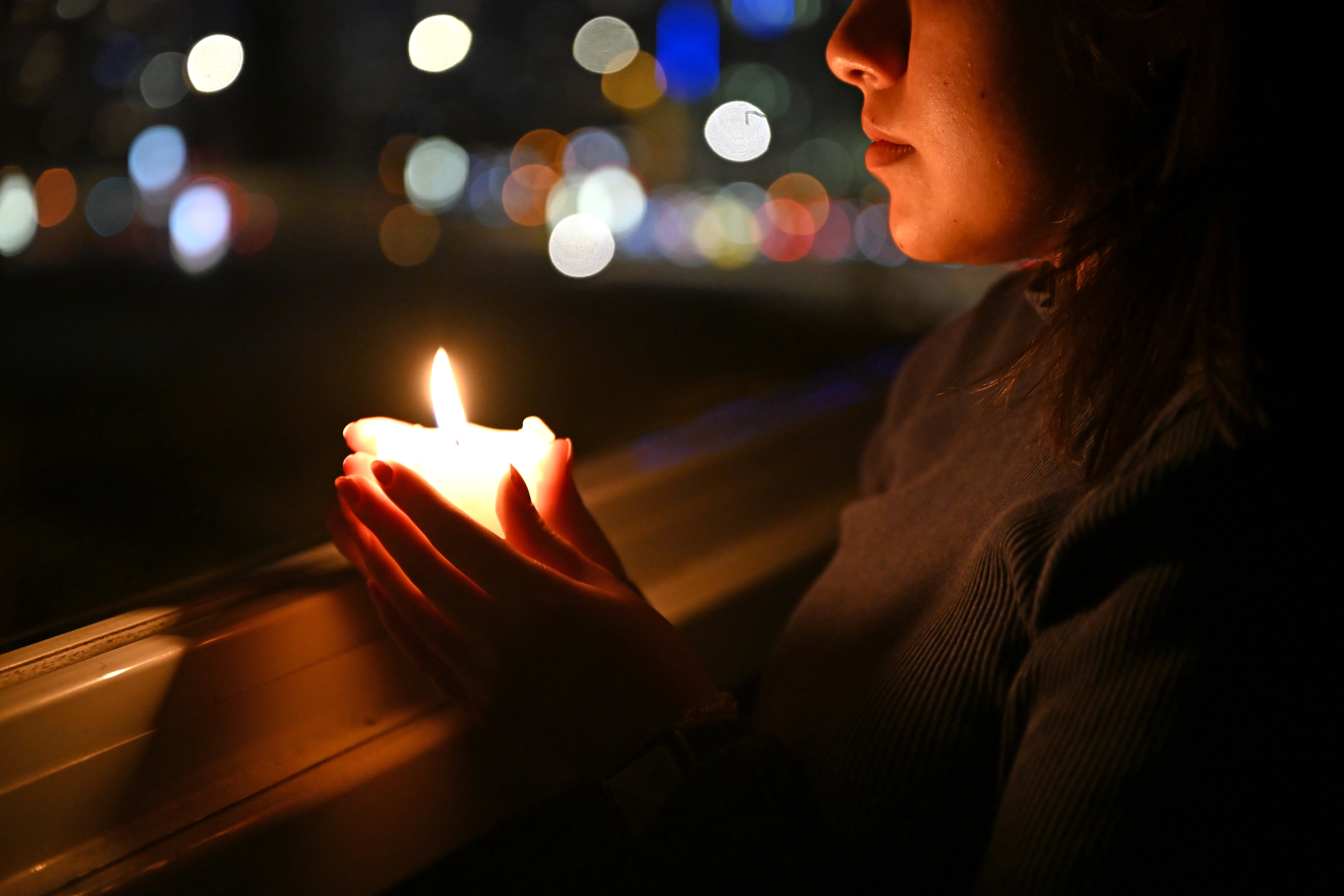 05.03.2026, International, Berlin: Eine Frau steht mit einer Kerze in einem dunklen Zimmer am Fenster. Die symbolische Kerzenbeleuchtung steht f&uuml;r die Aktion Earth Hour, bei der weltweit f&uuml;r eine Stunde die Lichter ausgeschaltet werden, um ein Zeichen f&uuml;r Klima- und Umweltschutz zu setzen. (Elisa Schu/dpa)
