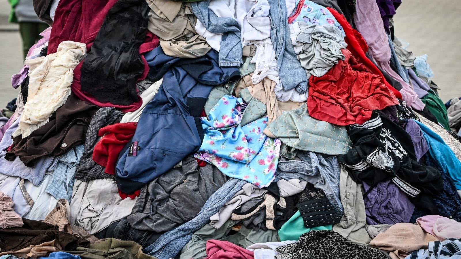 ARCHIV - 22.10.2025, Berlin: Mit weggeworfener Kleidung demonstriert die Umweltschutzorganisation Greenpeace vor dem Brandenburger Tor gegen den Fast-Fashion-Trend. Die Umweltsch&uuml;tzer setzen sich f&uuml;r ein Anti-Fast-Fashion-Gesetz ein. (zu dpa: &laquo;EU verbietet Firmen Vernichtung unverkaufter Kleidung&raquo;) Foto: Jens Kalaene/dpa +++ dpa-Bildfunk +++