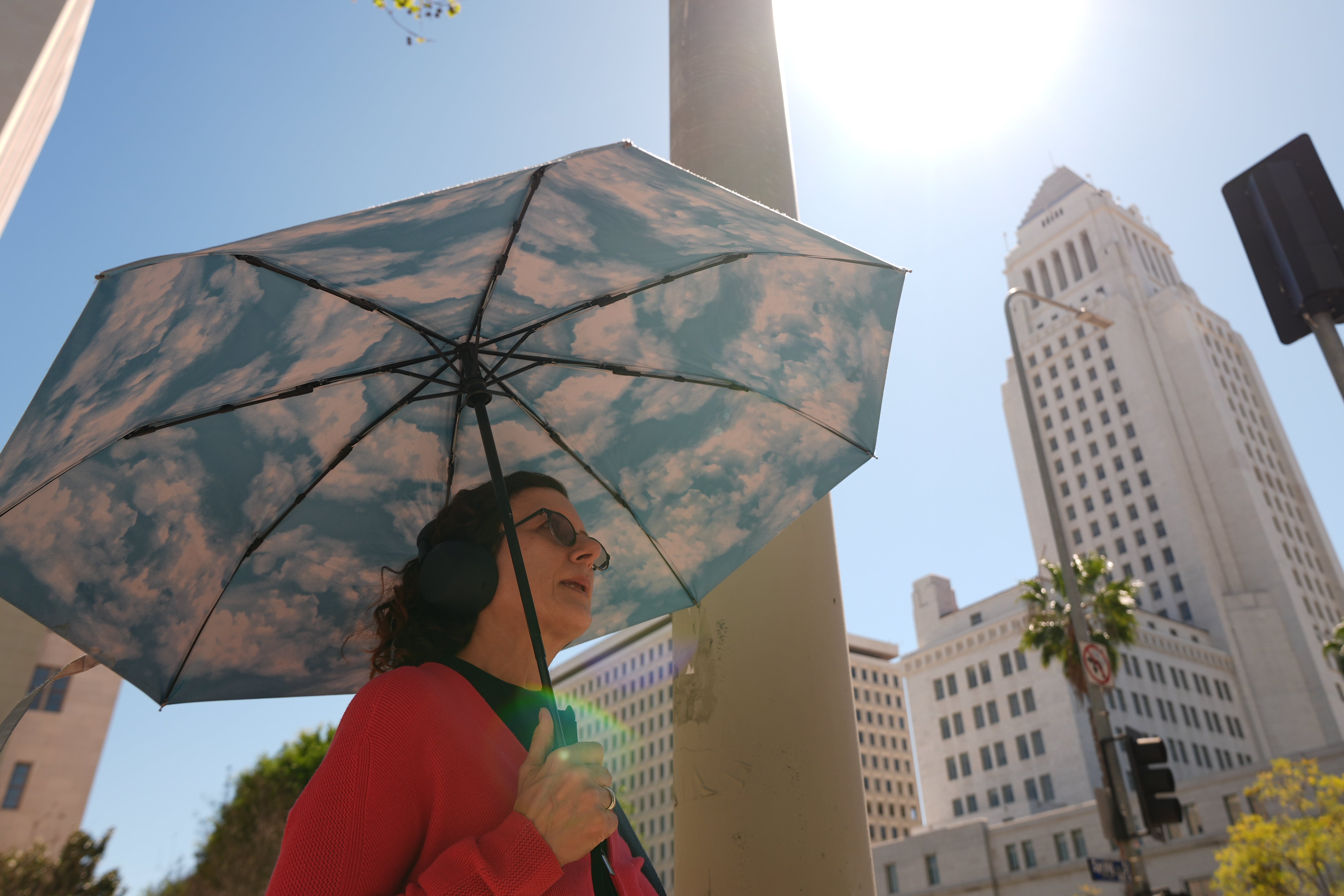 12. M&auml;rz 2026, Los Angeles: Ein Fu&szlig;g&auml;ngerin h&auml;lt an einem sonnigen Tag am neben dem Rathaus einen Regenschirm mit Wolkenmotiv in der Hand (AP Photo/Damian Dovarganes)