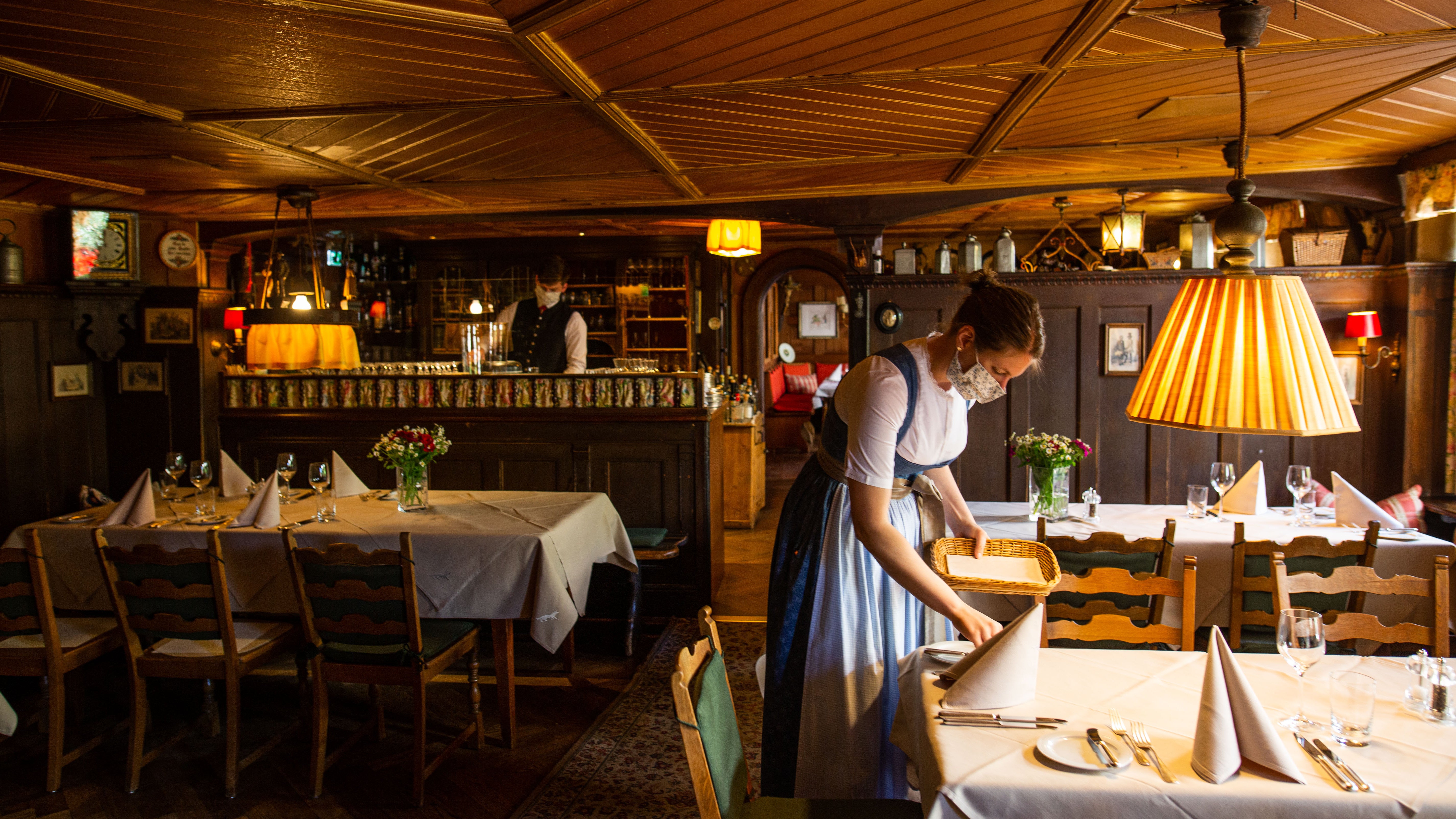 Baden-W&uuml;rttemberg, M&uuml;nstertal: Eine Frau deckt in einem Restaurant einen Tisch ein und tr&auml;gt Mundschutz.