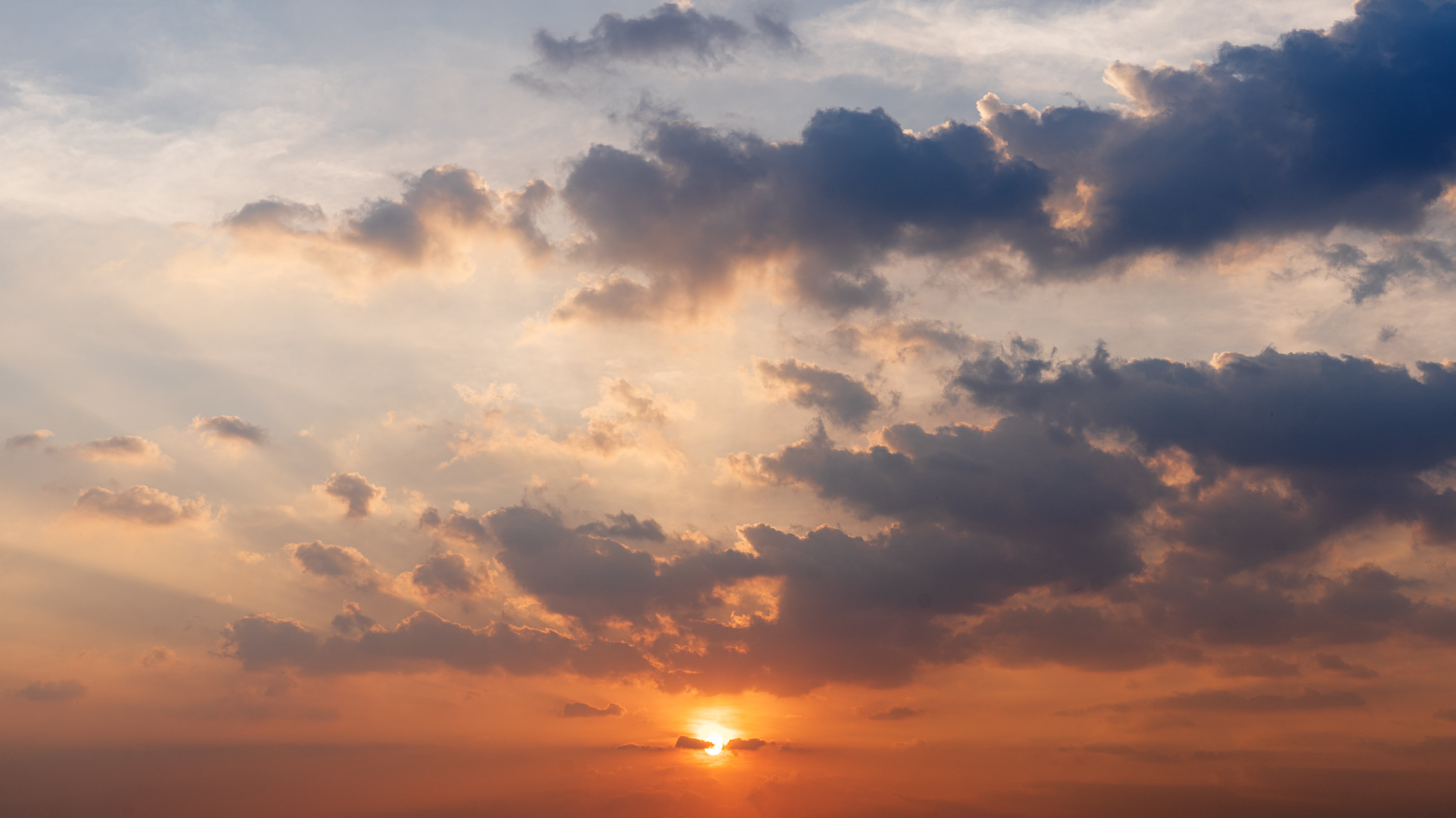 Ein Sonnenuntergang am Wolken verhangenen Abendhimmel (Symbolbild)
