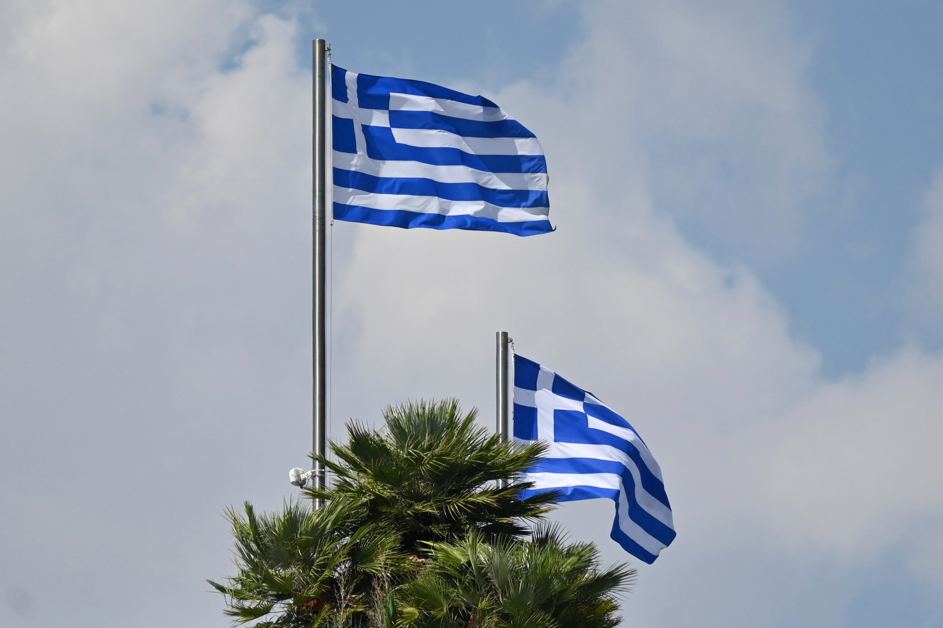 09.09.2025, Griechenland, Athen: Zwei griechische Nationalflaggen wehen vor einem bew&ouml;lkten Himmel im Wind. (Symbolbild) (Anna Ross/dpa)