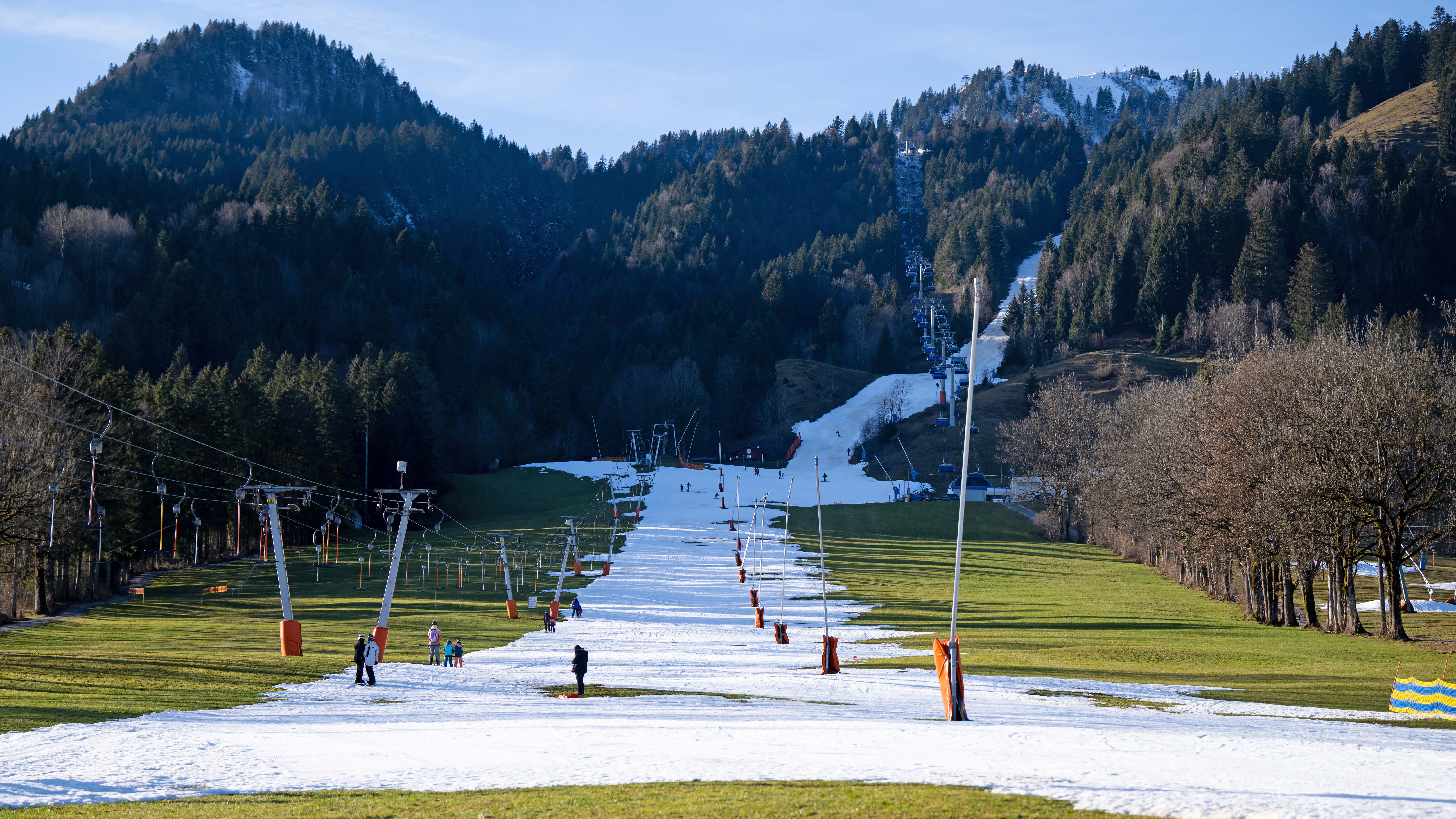 28.12.2022, Bayern, Lenggries: Wintersportler fahren am Draxlhang im Skigebiet Brauneck mit einem Schlepplift die Piste hinauf. Viele Skigebiete in Bayern leiden aktuell unter Schneemangel. Foto: Sven Hoppe/dpa +++ dpa-Bildfunk +++