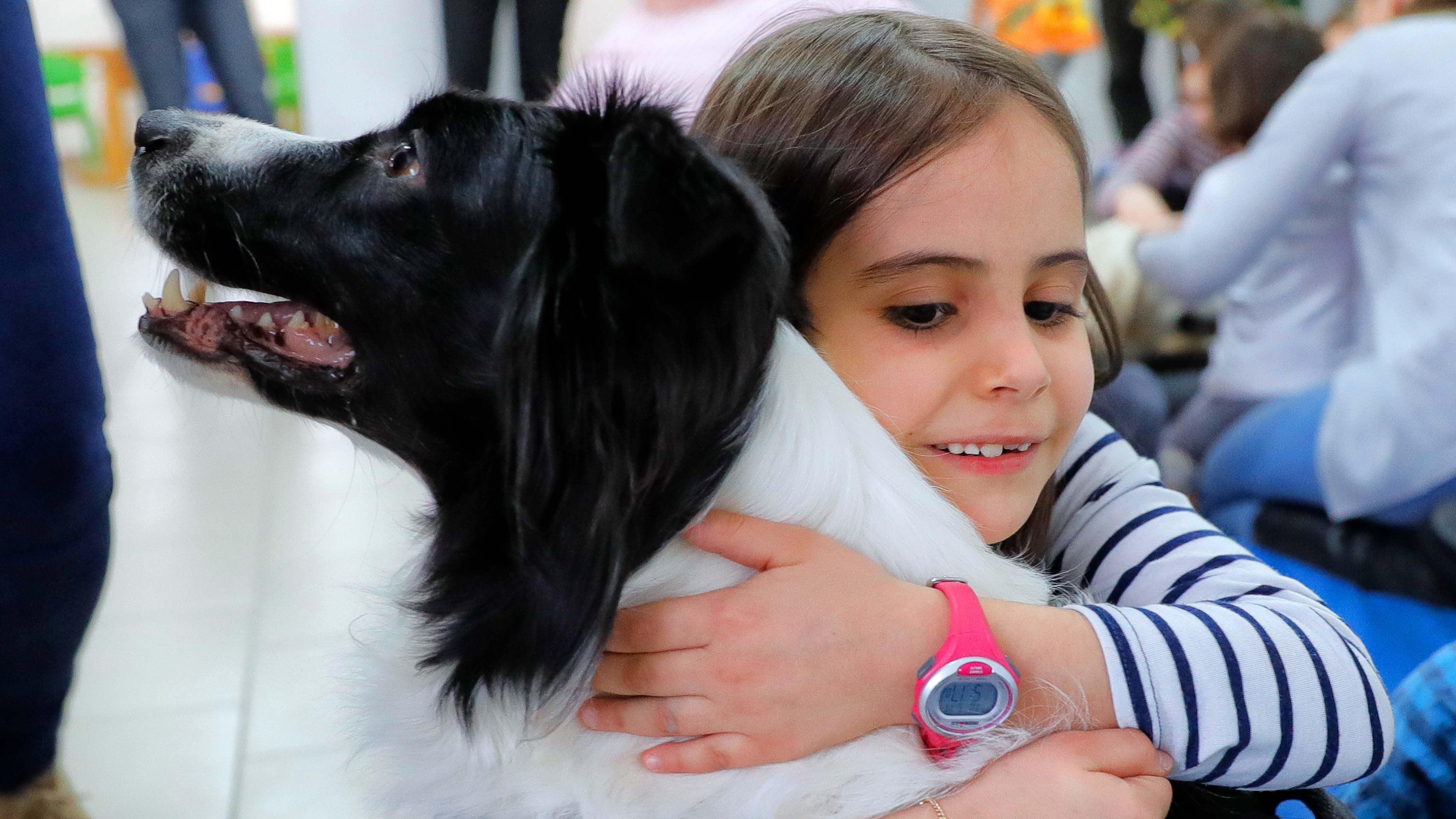 ARCHIV - 17.02.2017, Rum&permil;nien, Bukarest: Ein Kind umarmt in einer Einrichtung f&cedil;r Kinder mit Down-Syndrom einen speziell ausgebildeten Hund. In Zeiten von Kontaktsperren und Abstandsregeln w&permil;chst die Sehnsucht - die Sehnsucht nach N&permil;he, nach K&circ;rperkontakt, nach Umarmungen. Auch der diesj&permil;hrige &acute;Weltknuddeltag&ordf; steht im Zeichen von Corona. Foto: Vadim Ghirda/AP/dpa +++ dpa-Bildfunk +++