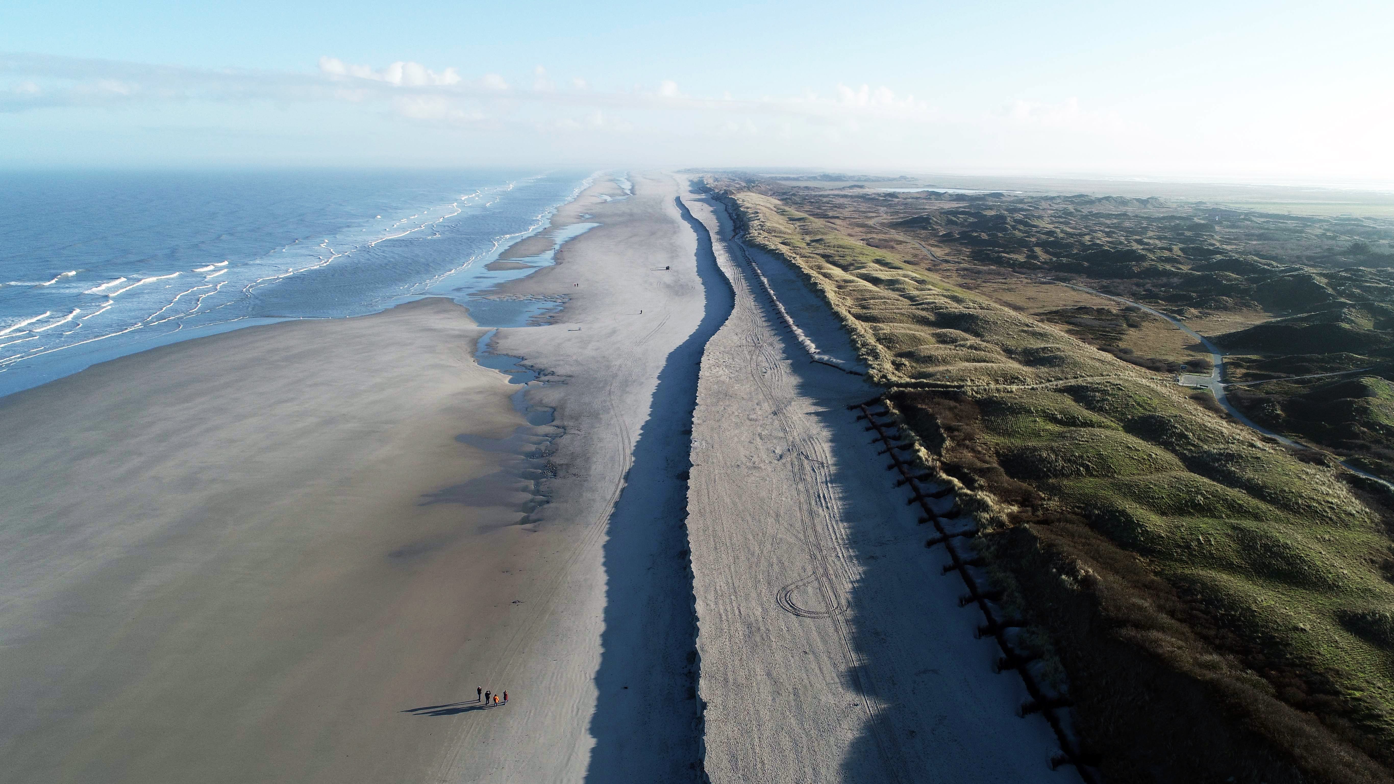 HANDOUT - 10.01.2022, Niedersachsen, Langeoog: Eine deutliche, etwa 500 Meter lange Abbruchkante hat sich nach den vergangenen Sturmfluten am Strand von Langeoog vor den D&uuml;nen des sogenannten Pirolatals gebildet (Luftaufnahme mit einer Drohne). Die Kante sei nach den Strandaufsp&uuml;lungen 2020 zu erwarten gewesen, teilte der f&uuml;r K&uuml;stenschutz zust&auml;ndige Landesbetrieb mit. Das Sanddepot wird nach jeder Sturmflut schmaler und sichert so die Schutzd&uuml;nen der Insel gegen Wellen und Sandabbr&uuml;che. (zu dpa: "Abbruchkante am Strand von Langeoog - keine Gefahr f&uuml;r K&uuml;stenschutz") Foto: -/NLWKN/dpa - ACHTUNG: Nur zur redaktionellen Verwendung im Zusammenhang mit der aktuellen Berichterstattung und nur mit vollst&auml;ndiger Nennung des vorstehenden Credits +++ dpa-Bildfunk +++
