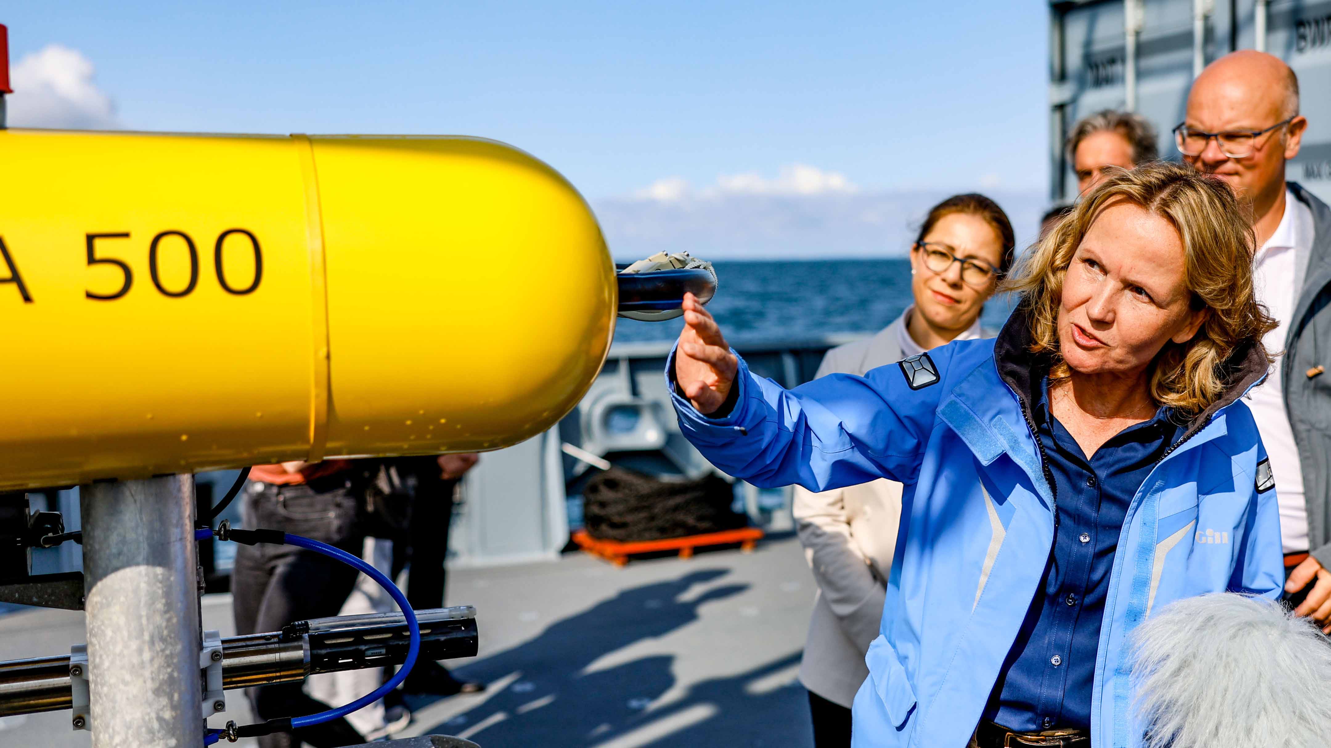 ARCHIV - 01.09.2023, Schleswig-Holstein, Kiel: Bundesumweltministerin Steffi Lemke (B&uuml;ndnis90/Die Gr&uuml;nen) informiert sich an Bord eines Marineschiffes vor einem "AUV" (Autonomous Underwater Vehicle, welches zur Kartierung und Suche von Munitionsresten im Wasser eingesetzt wird) &uuml;ber die Bergung von Munitionsaltlasten in der Ostsee. (zu dpa: "Dauerhafte Bergung von Munition aus Meer ab 2026 geplant") Foto: Axel Heimken/dpa +++ dpa-Bildfunk +++