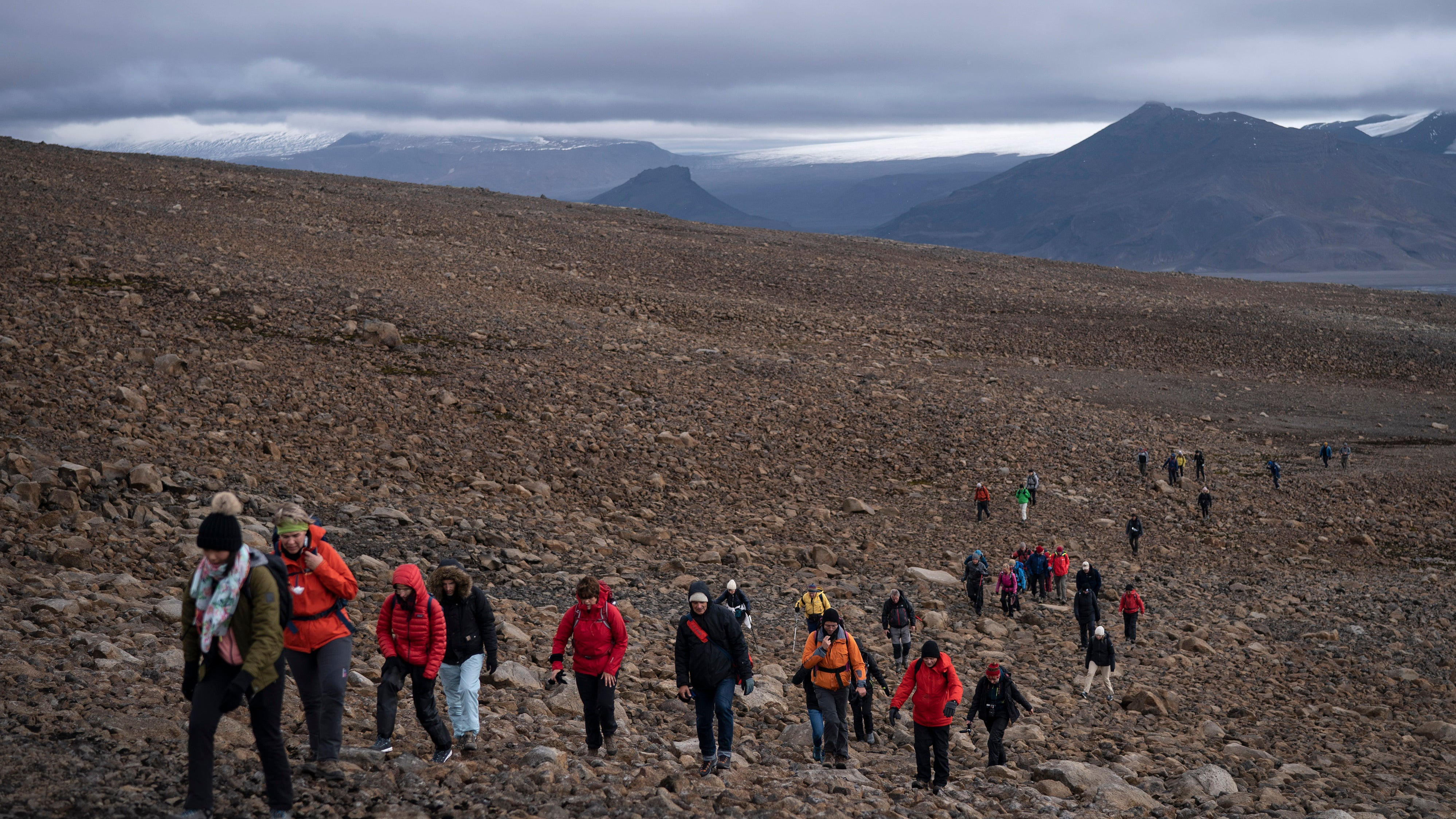 Zahlreiche Menschen wandern &uuml;ber das Ger&ouml;ll am Okj&ouml;kull zu einer Gedenkveranstaltung f&uuml;r den vergangenen Gletscher. 