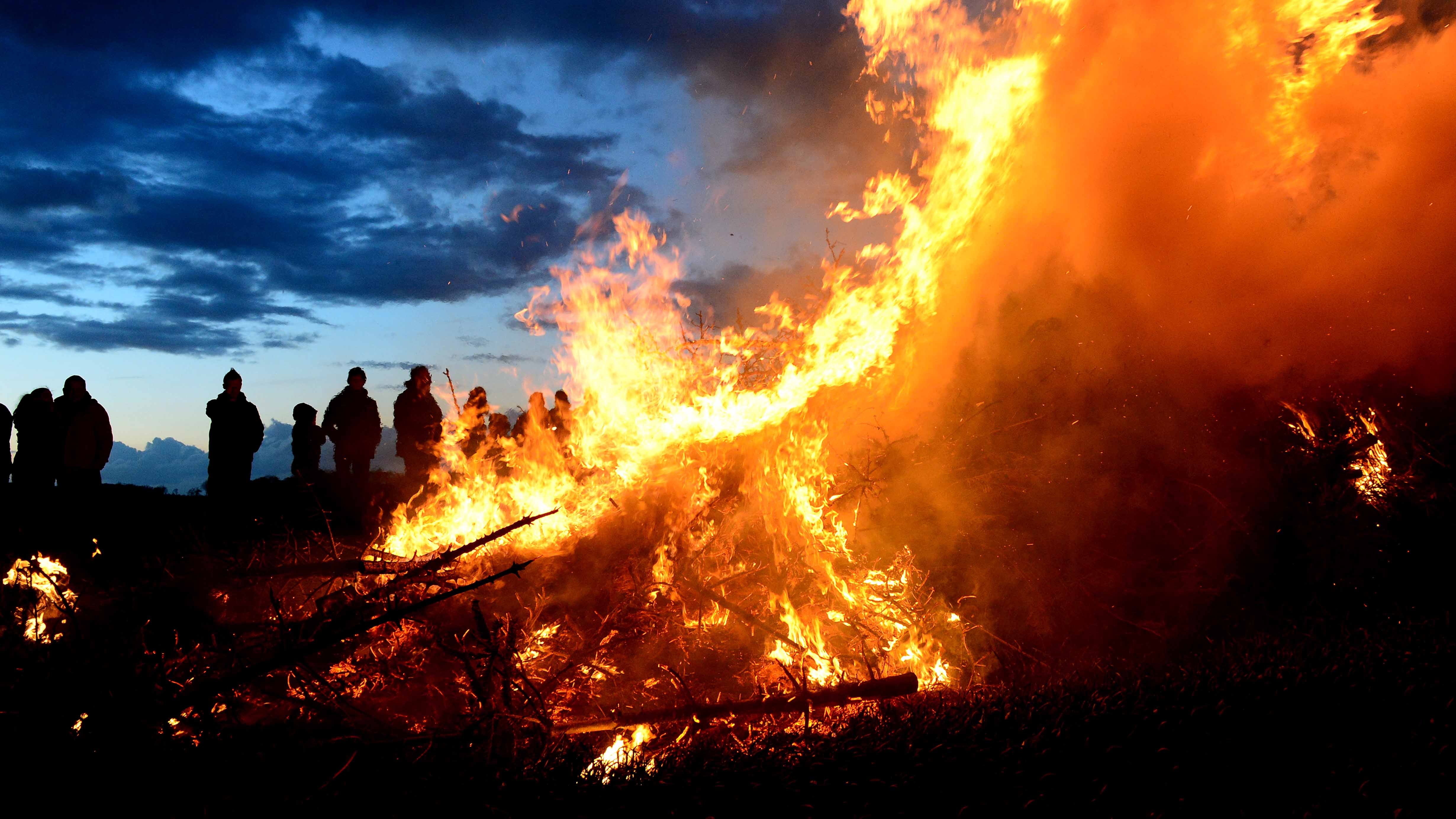 ARCHIV - 15.04.2017, Niedersachsen, Wartjenstedt: Zuschauer stehen bei einem traditionellen Osterfeuer. Wegen der anhaltenden Trockenheit diskutieren zahlreiche Kommunen in Nordrhein-Westfalen, ob die traditionellen Osterfeuer in diesem Jahr stattfinden k&circ;nnen. In mehreren Kreisen etwa im Sauerland sind die Ordnungs&permil;mter im Austausch mit der Feuerwehr. (zu dpa: &acute;Trockenheit k&circ;nnte zu Absagen bei Osterfeuern f&cedil;hren&ordf;) Foto: Maurizio Gambarini/dpa +++ dpa-Bildfunk +++