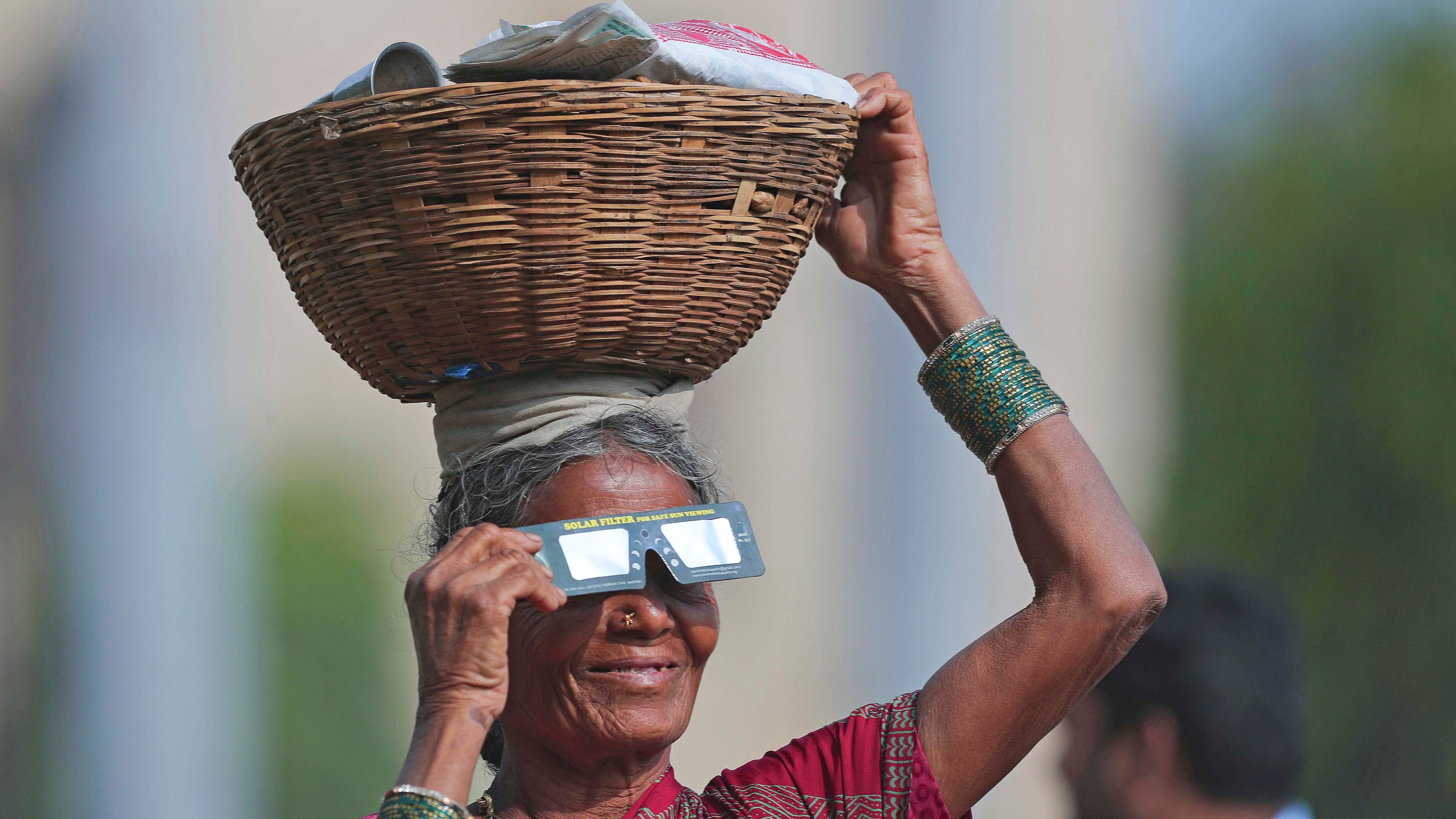 dpatopbilder - 26.12.2019, Indien, Hyderabad: Eine Straﬂenverk&permil;uferin h&permil;lt eine Schutzbrille vor ihren Augen, um eine partielle Sonnenfinsternis zu beobachten. Foto: Mahesh Kumar A/AP/dpa +++ dpa-Bildfunk +++