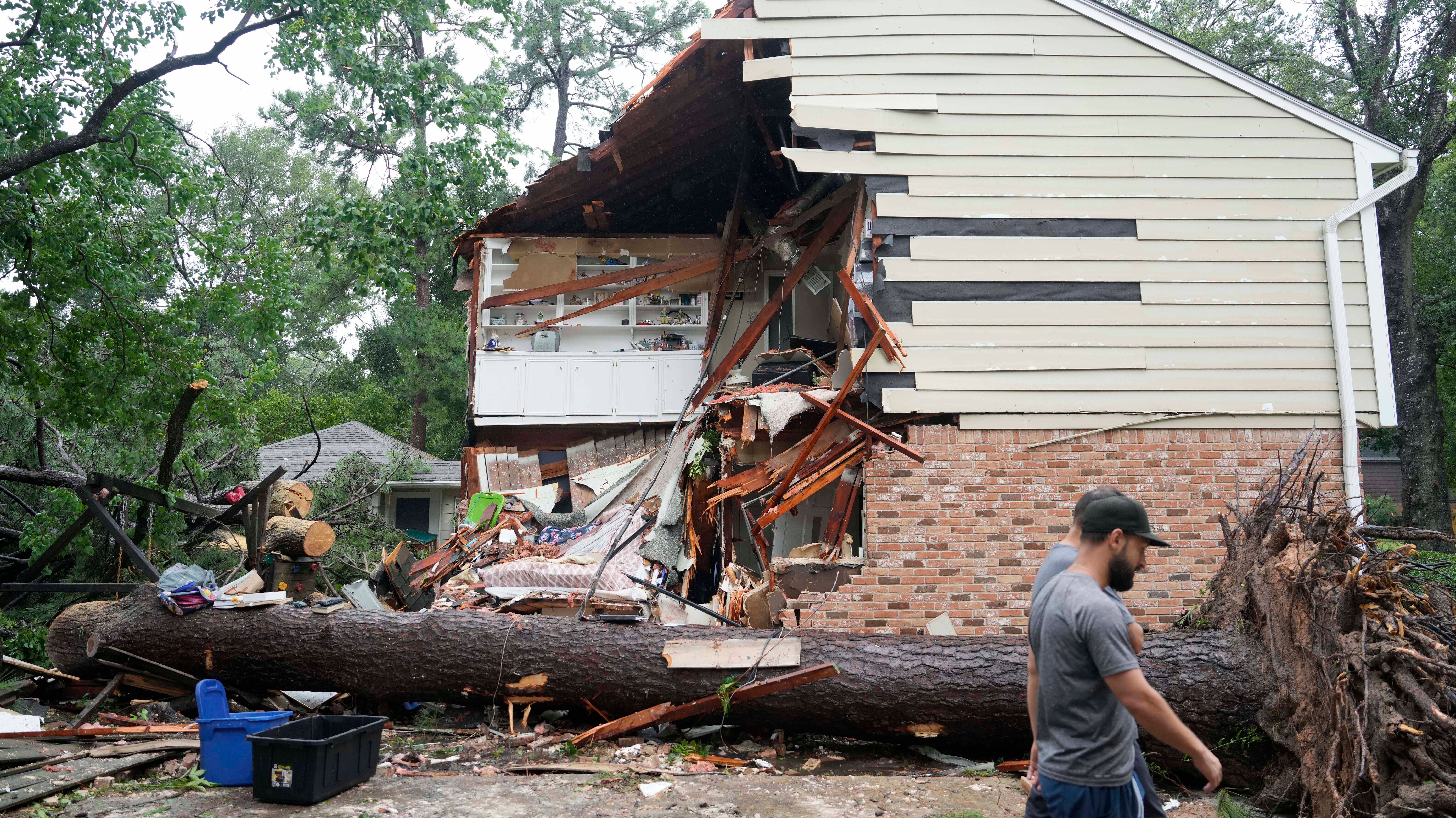 08.07.2024, USA, Houston: Menschen versammeln sich vor einem Haus im Block 17400 des Rustic Canyon Trail, wo Maria Laredo, 74, starb, nachdem ein Baum w&auml;hrend des Hurrikans Beryl in Houston auf ihr Schlafzimmer im zweiten Stock gest&uuml;rzt war. Foto: Melissa Phillip/Houston Chronicle via AP/dpa - ACHTUNG: Nur zur redaktionellen Verwendung und nur mit vollst&auml;ndiger Nennung des vorstehenden Credits +++ dpa-Bildfunk +++