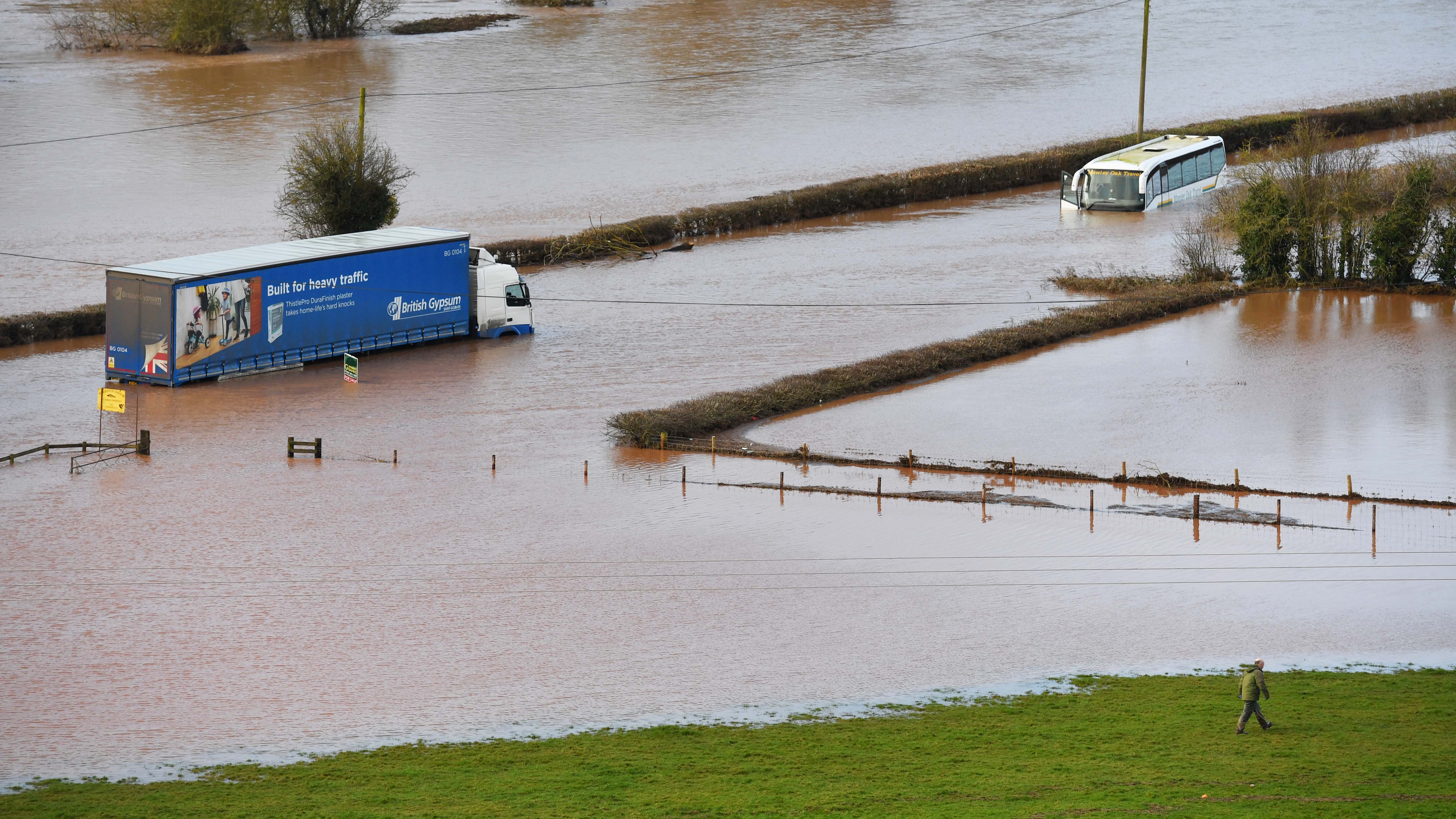 17.02.2020, Groﬂbritannien, Lindridge: Ein LKW (l) und ein Reisebus stehen auf der A443 in Hochwasser. Das Hochwasser-Risiko in Groﬂbritannien wird nach Experten-Ansicht noch Tage bestehen bleiben. Sturm &acute;Dennis&ordf; hatte am Wochenende enorme Regenmengen mitgebracht. In einigen Regionen regnete es an einem Tag so viel wie sonst im Monatsdurchschnitt. Foto: Jacob King/PA Wire/dpa +++ dpa-Bildfunk +++