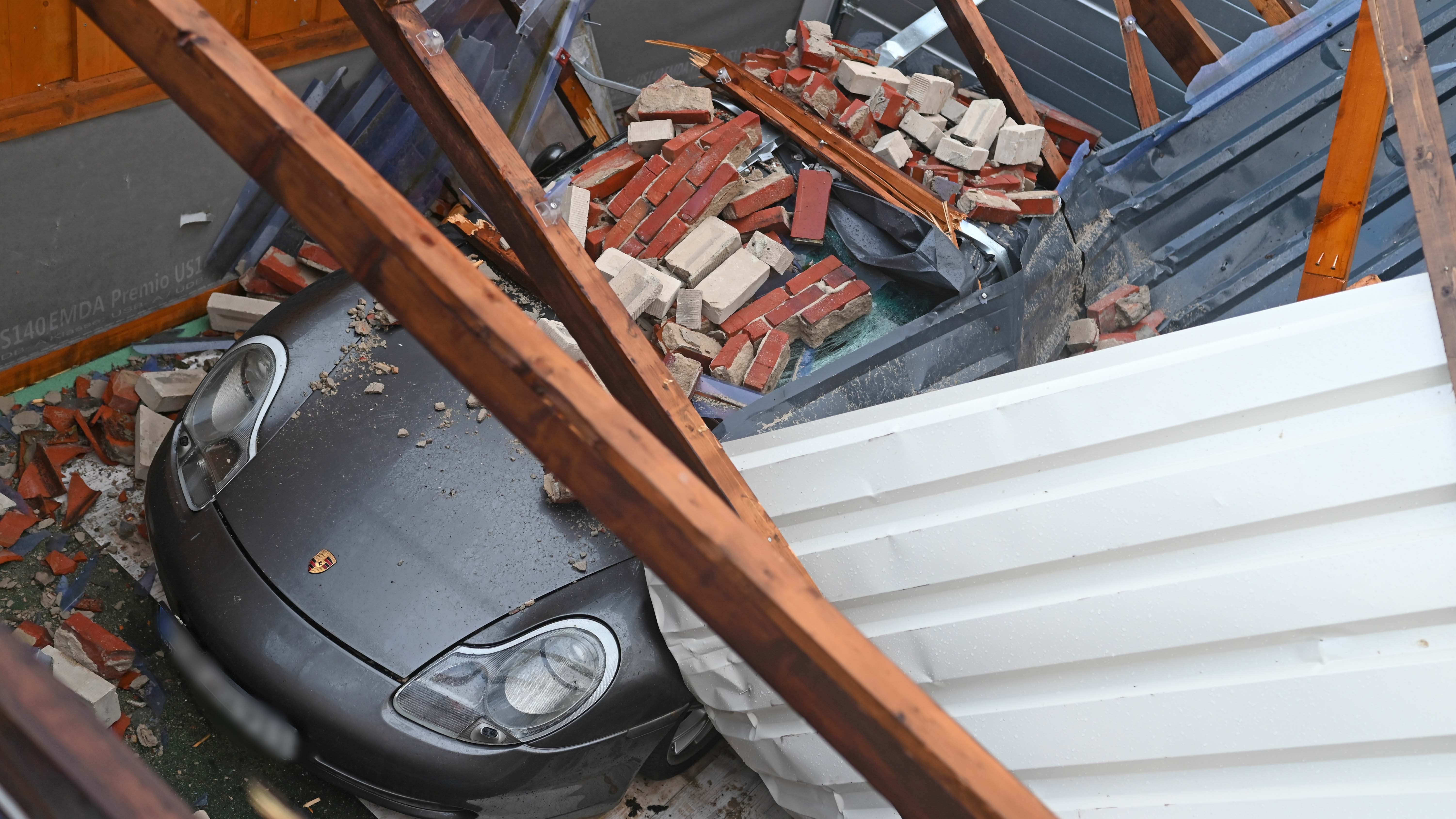 dpatopbilder - 19.02.2022, Niedersachsen, Eversmeer: Reste eines eingest&uuml;rzten Daches liegen nach dem Orkan Zeynep auf einem Porsche. Sturmtief &laquo;Zeynep&raquo; zieht mit schweren Sturmb&ouml;en und kr&auml;ftigen Schauern &uuml;ber Deutschland hinweg. Foto: Lars-Josef Klemmer/dpa +++ dpa-Bildfunk +++