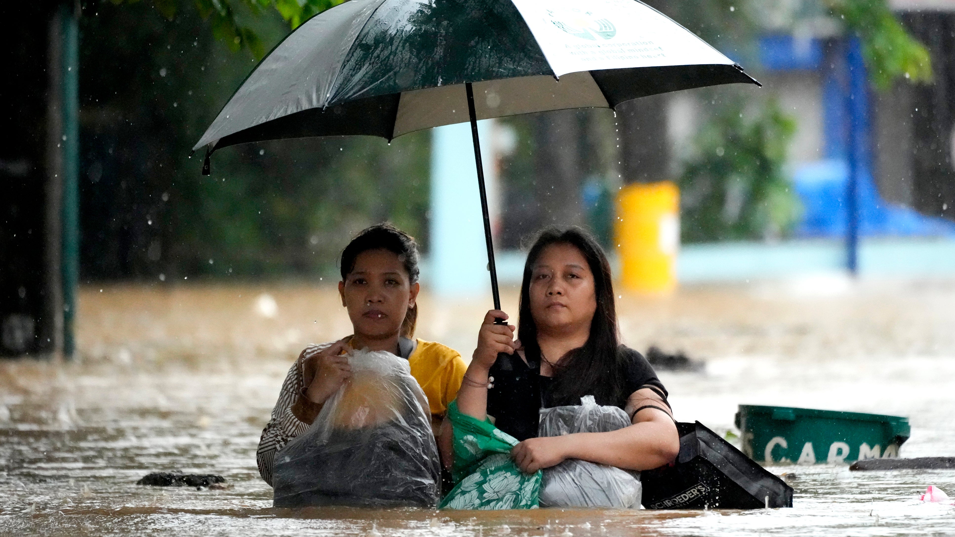 Cainta, Philippinen, 2. September 2024: Anwohner sch&uuml;tzen ihr Hab und Gut, w&auml;hrend sie sich durch eine &uuml;berflutete Stra&szlig;e k&auml;mpfen, die Folge der heftigen Regenf&auml;llen des Tropensturms Yagi (lokal Enteng genannt) sind. (AP Photo/Aaron Favila)
