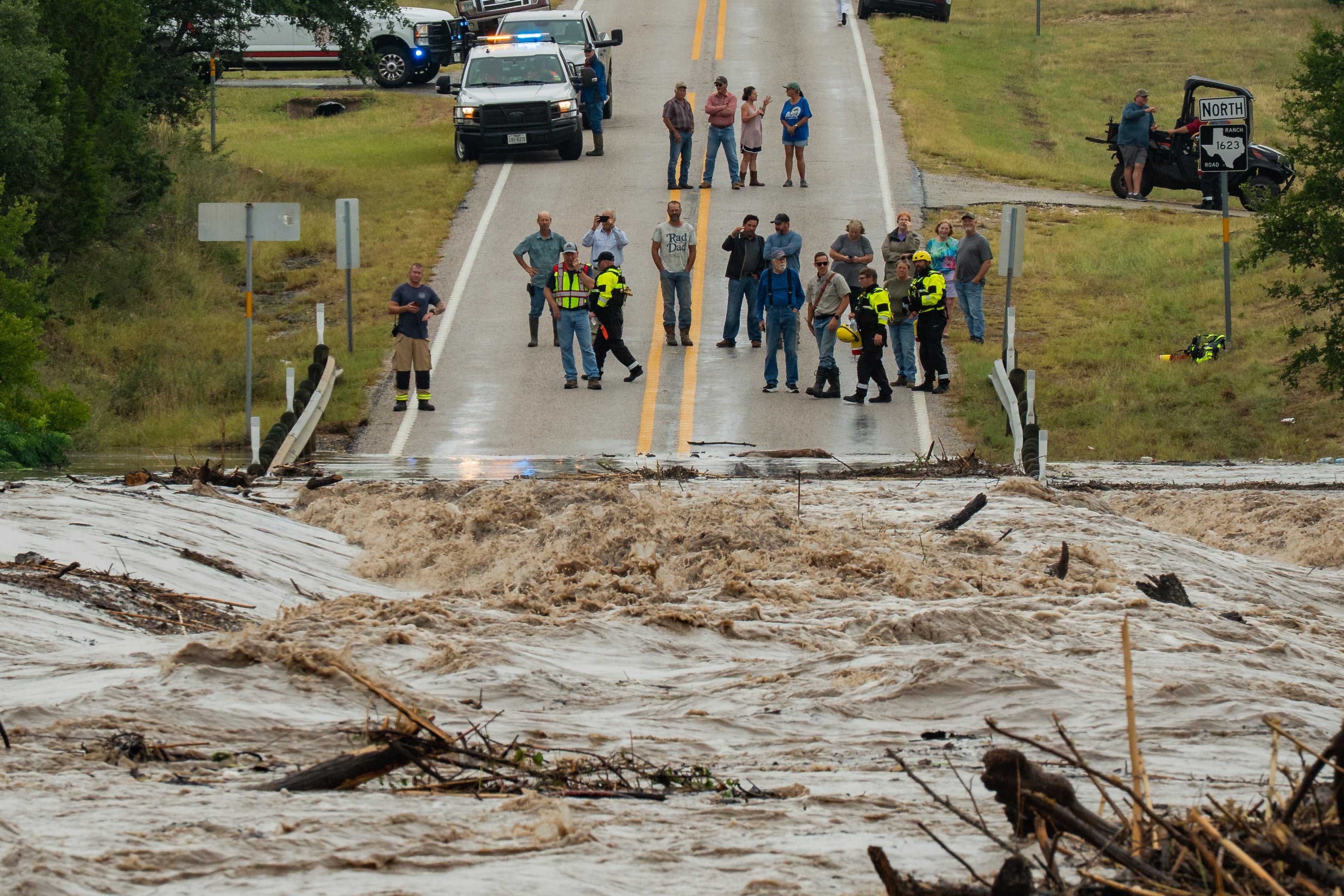 ACHTUNG: Nur zur redaktionellen Verwendung und nur mit vollst&auml;ndiger Nennung des Credits

16.07.2026, USA, Stonewall: Menschen stehen zusammen und beobachten, wie der Perdenales River die Ranch Road 1623 &uuml;berflutet. (Mikala Compton/Austin American-Statesman/AP/dpa)
