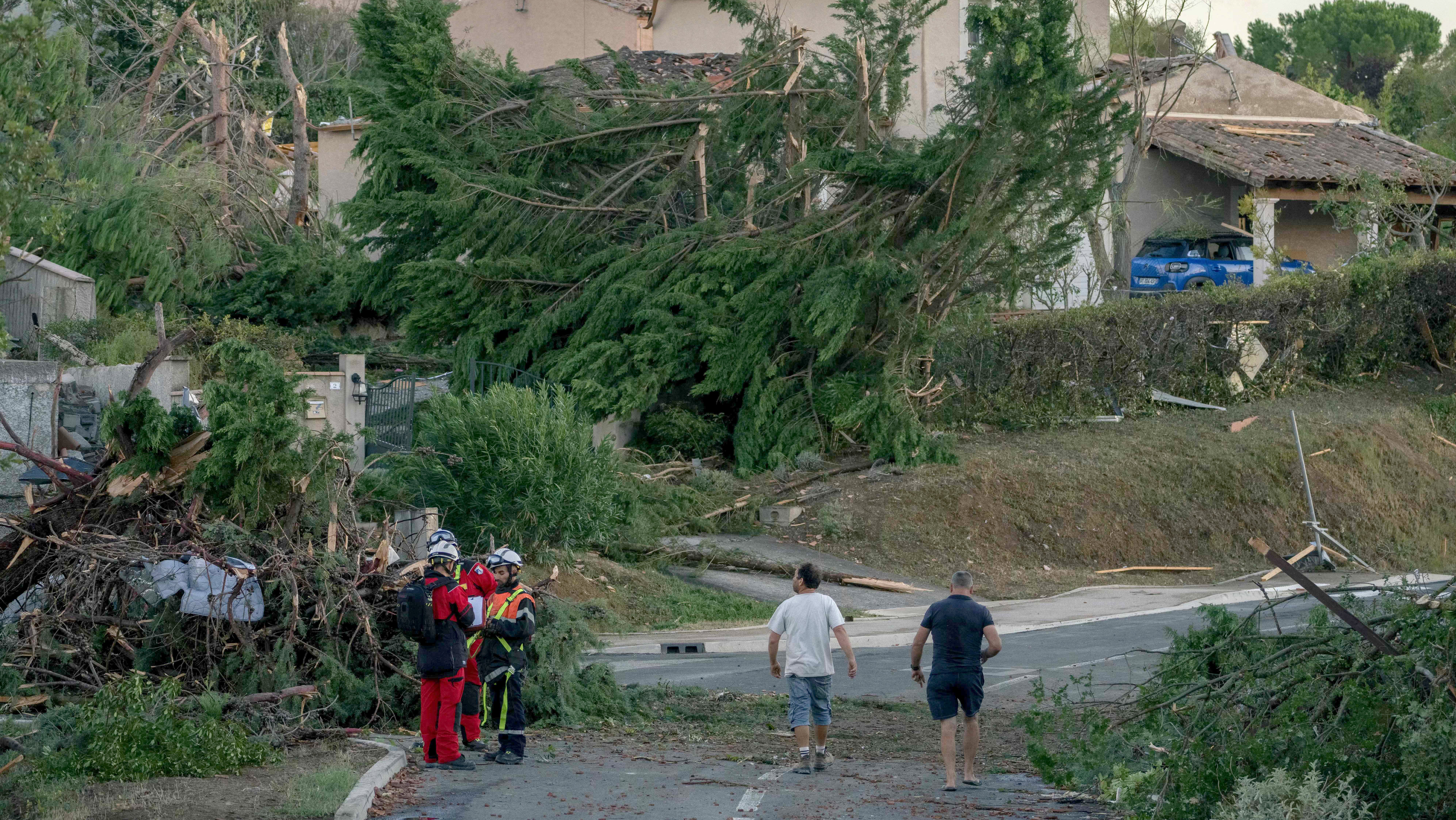 24.08.2026, Frankreich, Pompas: Feuerwehrleute stehen nach einem Tornado an umgest&uuml;rzten B&auml;umen und besch&auml;digten H&auml;usern. (Idriss Bigou-Gilles/AFP/dpa)