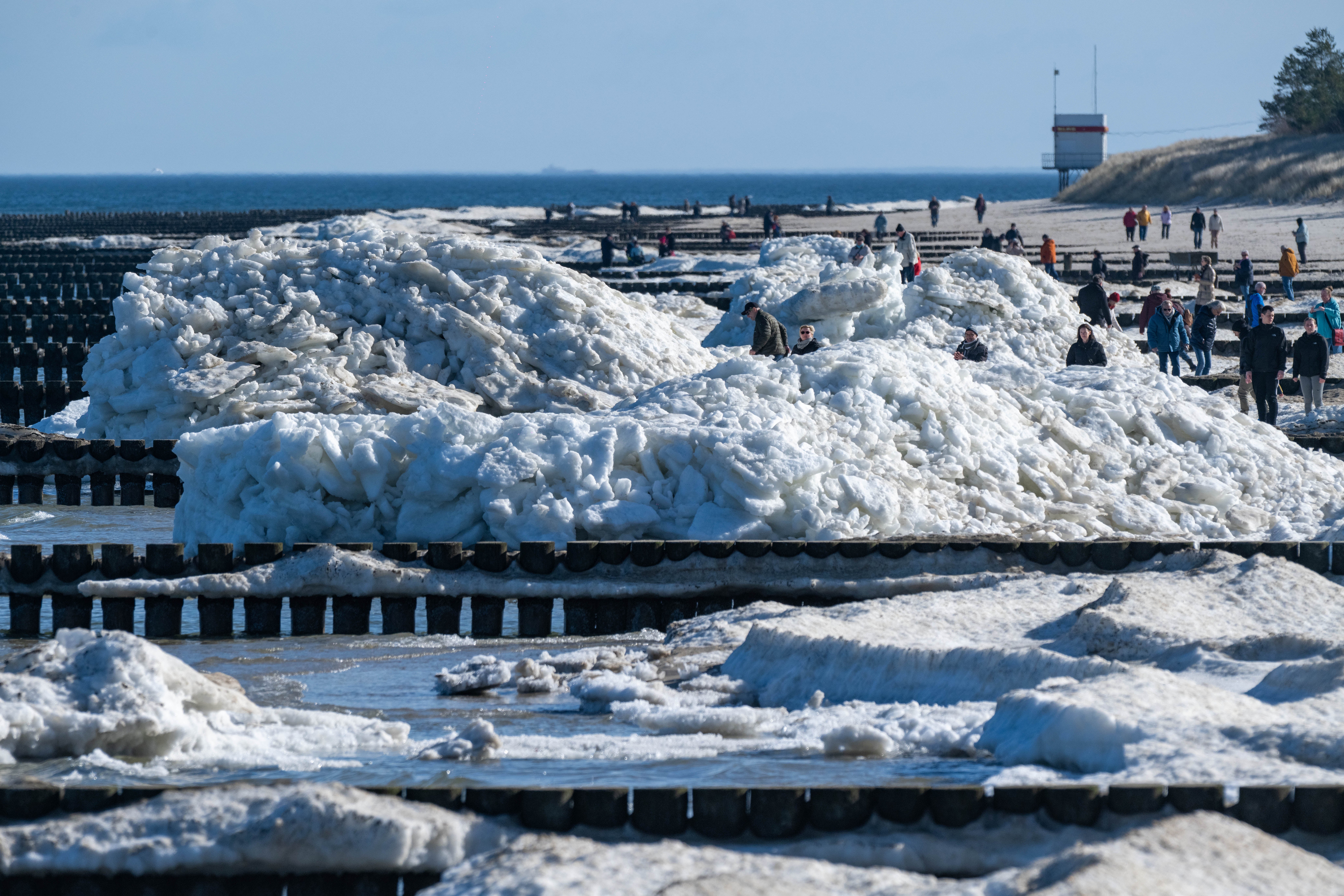 01.03.2026, Mecklenburg-Vorpommern, Zempin: Touristen und Einwohner spazieren am Strand von Zempin. Dort t&uuml;rmen sich auch am meteorologischer Fr&uuml;hlingsanfang noch Eisschollen auf mehreren Metern H&ouml;he. (Stefan Sauer/dpa)

