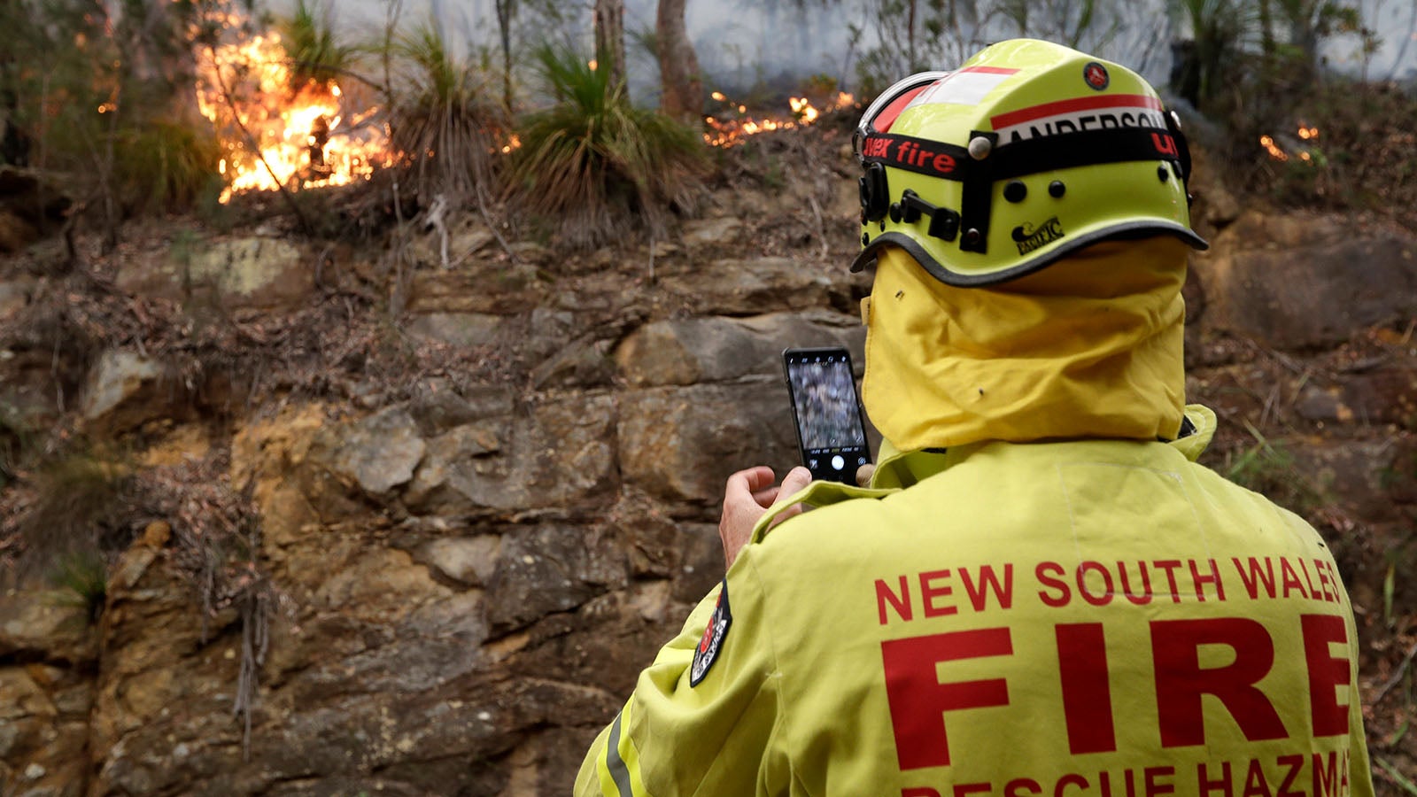 10.12.2019, Australien, Mangrove Mountain: Ein Feuerwehrmann fotografiert mit seinem Telefon den Rand des Feuers in der N&auml;he des Mangrove Mountain, n&ouml;rdlich von Sydney. In Australien bekommen die Rettungskr&auml;fte Die gewaltigen Buschbr&auml;nde weiterhin nicht unter Kontrolle Foto: Rick Rycroft/AP/dpa +++ dpa-Bildfunk +++