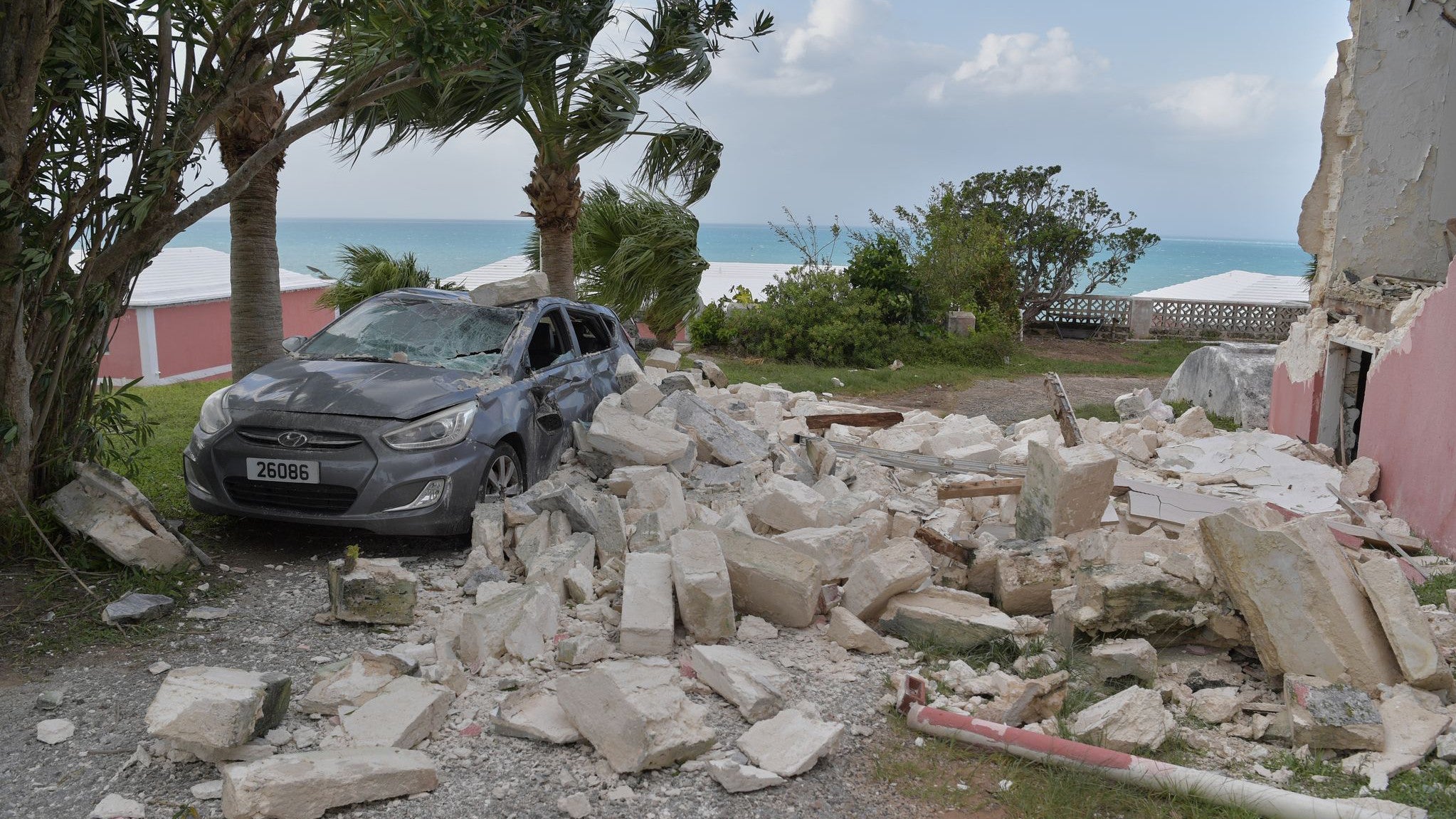 2. Oktober 2025, Hamilton, Bermuda: Nach dem Durchzug des Hurrikans Imelda steht ein ein Auto durch Tr&uuml;mmer besch&auml;digt auf einer Stra&szlig;e (AP Photo/Anthony Wade)