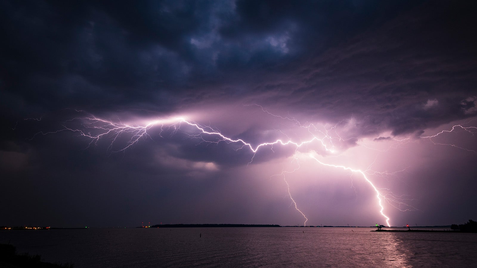 Lightning in the dark night sky over a lake during summer in Flevoland, The Netherlands