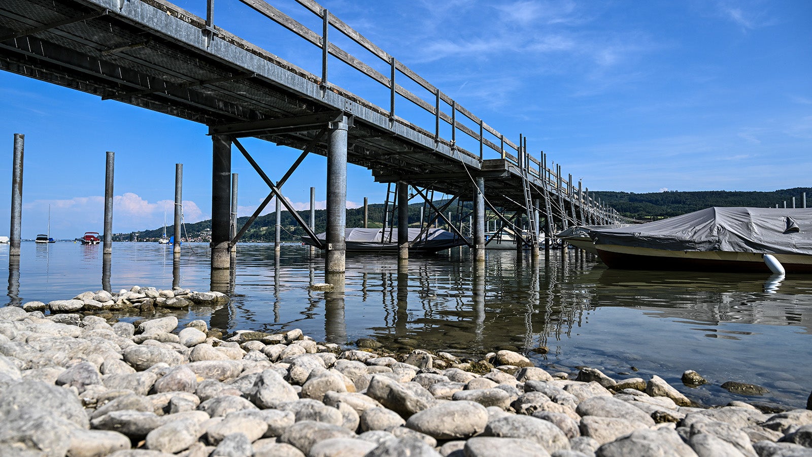 28.07.2022, Baden-W&uuml;rttemberg, Gaienhofen: Mehrere Liegepl&auml;tze sind im Hafen von Gaienhofen unbesetzt, weil der Bodensee Niedrigwasser hat. Steine sind am&nbsp;Ufer zu sehen, die hier sonst meist &uuml;bersp&uuml;lt sind. Foto: Felix K&auml;stle/dpa +++ dpa-Bildfunk +++