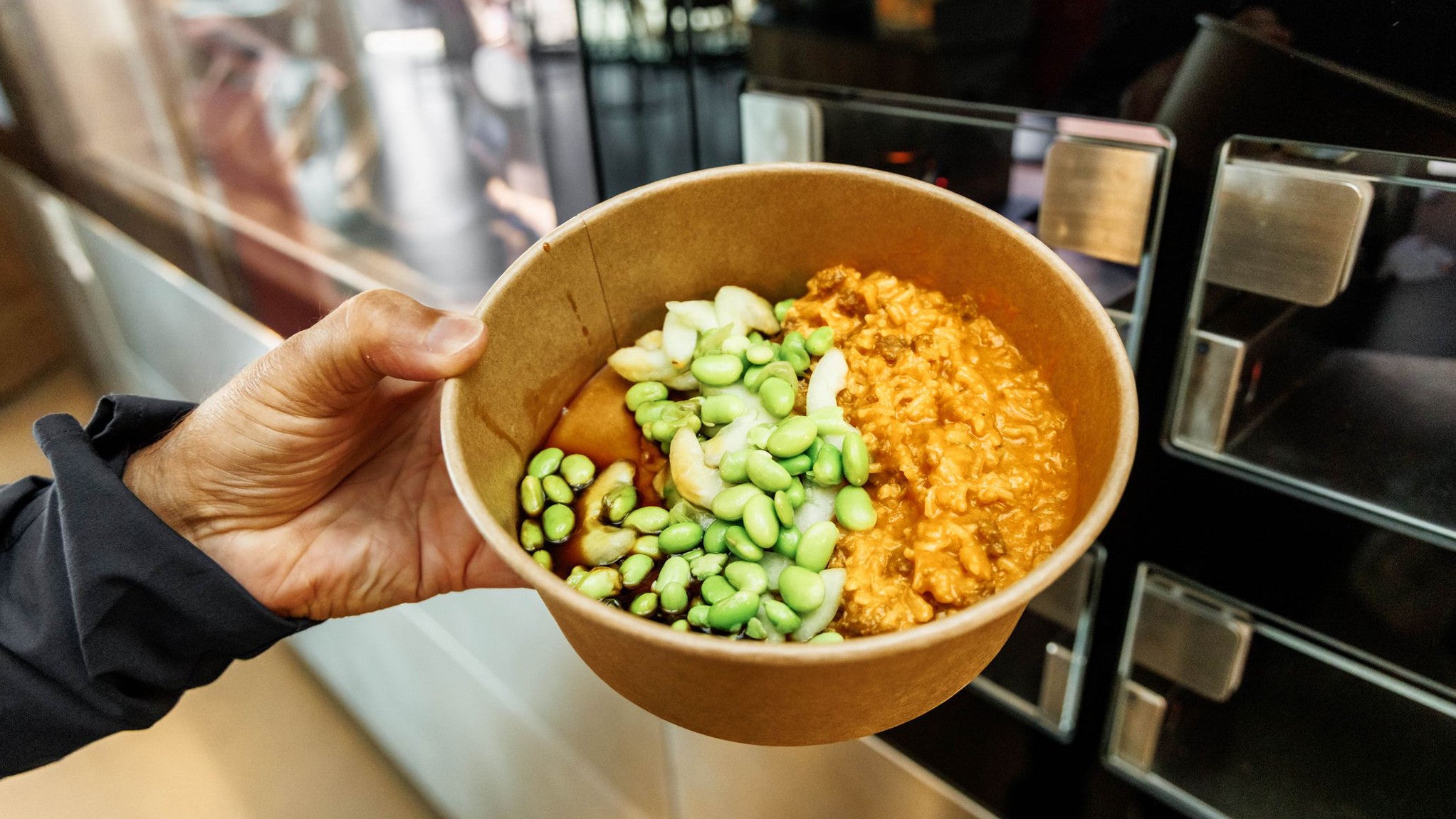 20.07.2023, Schleswig-Holstein, Gr&ouml;mitz: Eine Person h&auml;lt ein von einem Kochroboter zubereitetes Gericht in der Hand. Manchen Lebensmitteln sieht man den Zuckergehalt nicht auf den ersten Blick an. (Markus Scholz/dpa)

