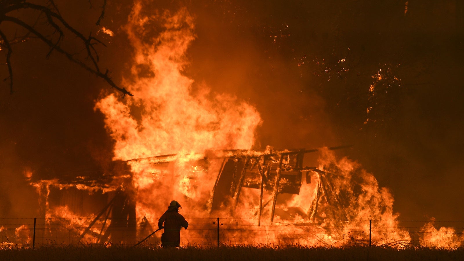 21.12.2019, Australien, Bilpin: Ein Feuerwehrmann bek&auml;mpft die Flammen des &laquo;Gosper Mountain&raquo;-Feuers, die ein Geb&auml;ude erreicht haben. Die Lage im Kampf gegen die Buschfeuer in Australien spitzt sich zu. Foto: Dan Himbrechts/AAP/dpa 