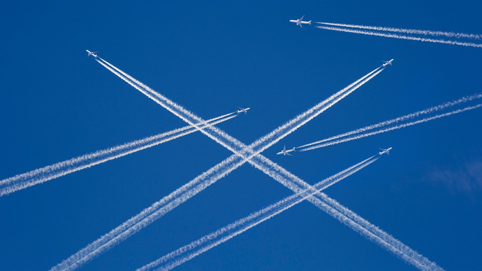 A lot of passenger airplanes on the air, busy air traffic, traveling high season starts concept. White planes against blue sky.  Photo manipulation.
