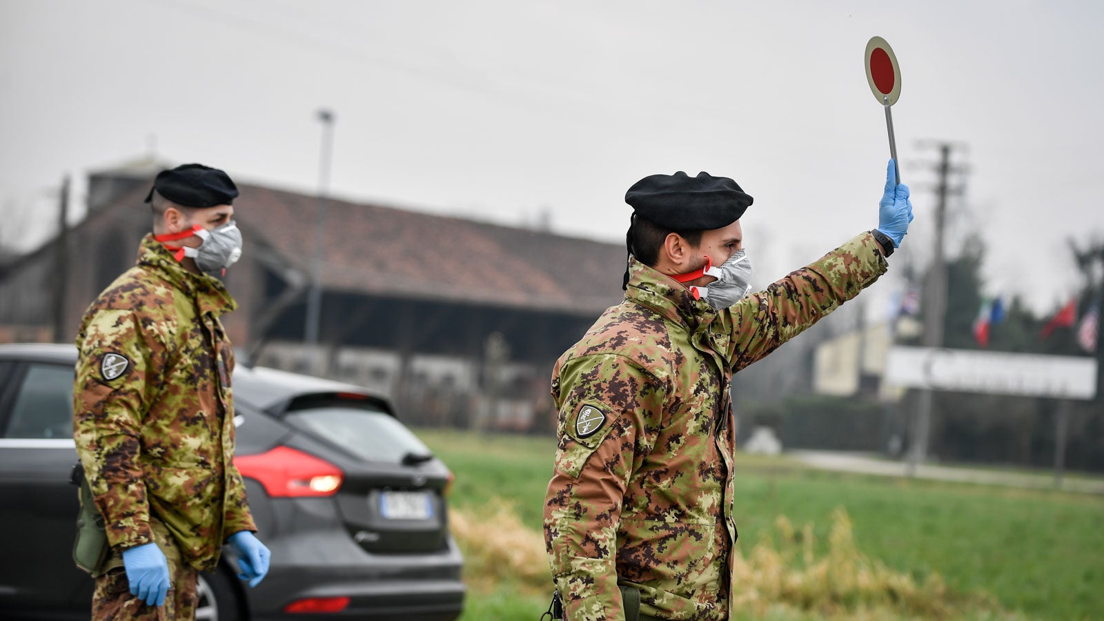 ARCHIV - 25.02.2020, Italien, Turano Lodigiano: Ein Soldat mit Atemschutzmaske h?lt an einer Stra?ensperre vor der roten Zone von Turano Lodigiano eine Winkerkelle in die H?he. Die italienische Regierung erw?gt nach Medienberichten wegen der Coronavirus-Krise die Sperrung der Lombardei und weiterer Gebiete. Foto: Claudio Furlan/LaPresse via ZUMA Press/dpa +++ dpa-Bildfunk +++