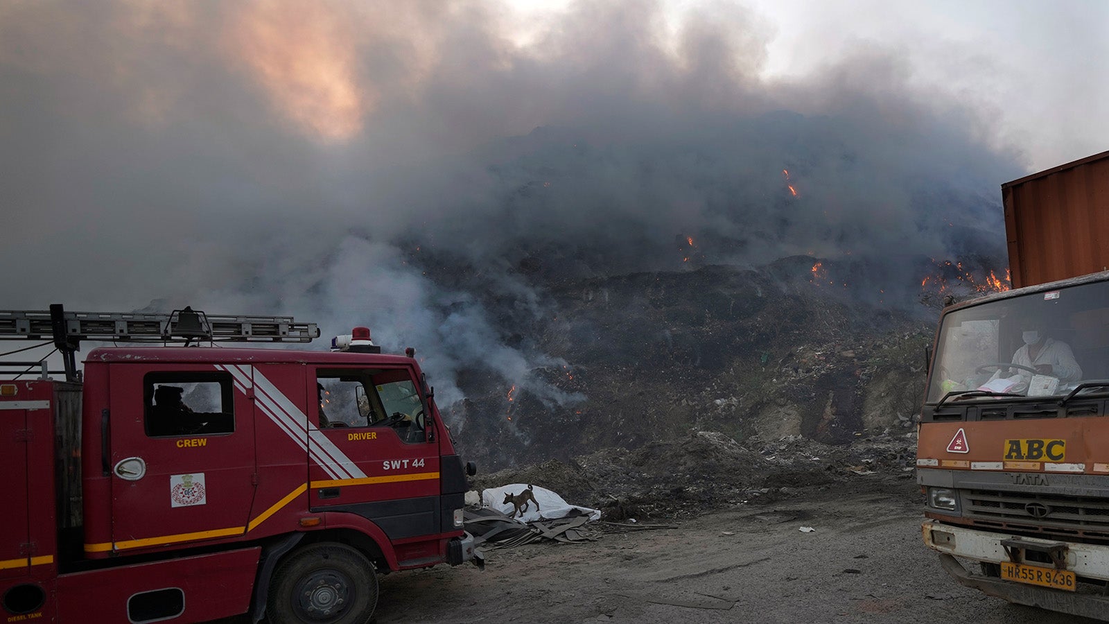 A Delhi fire tender waits during a fire at the Bhalswa landfill in New Delhi, India, Wednesday, April 27, 2022. The landfill that covers an area bigger than 50 football fields, with a pile taller than a 17-story building caught fire on Tuesday evening, turning into a smoldering heap that blazed well into the night. India's capital, which like the rest of South Asia is in the midst of a record-shattering heat wave, was left enveloped in thick acrid smoke. (AP Photo/Manish Swarup)