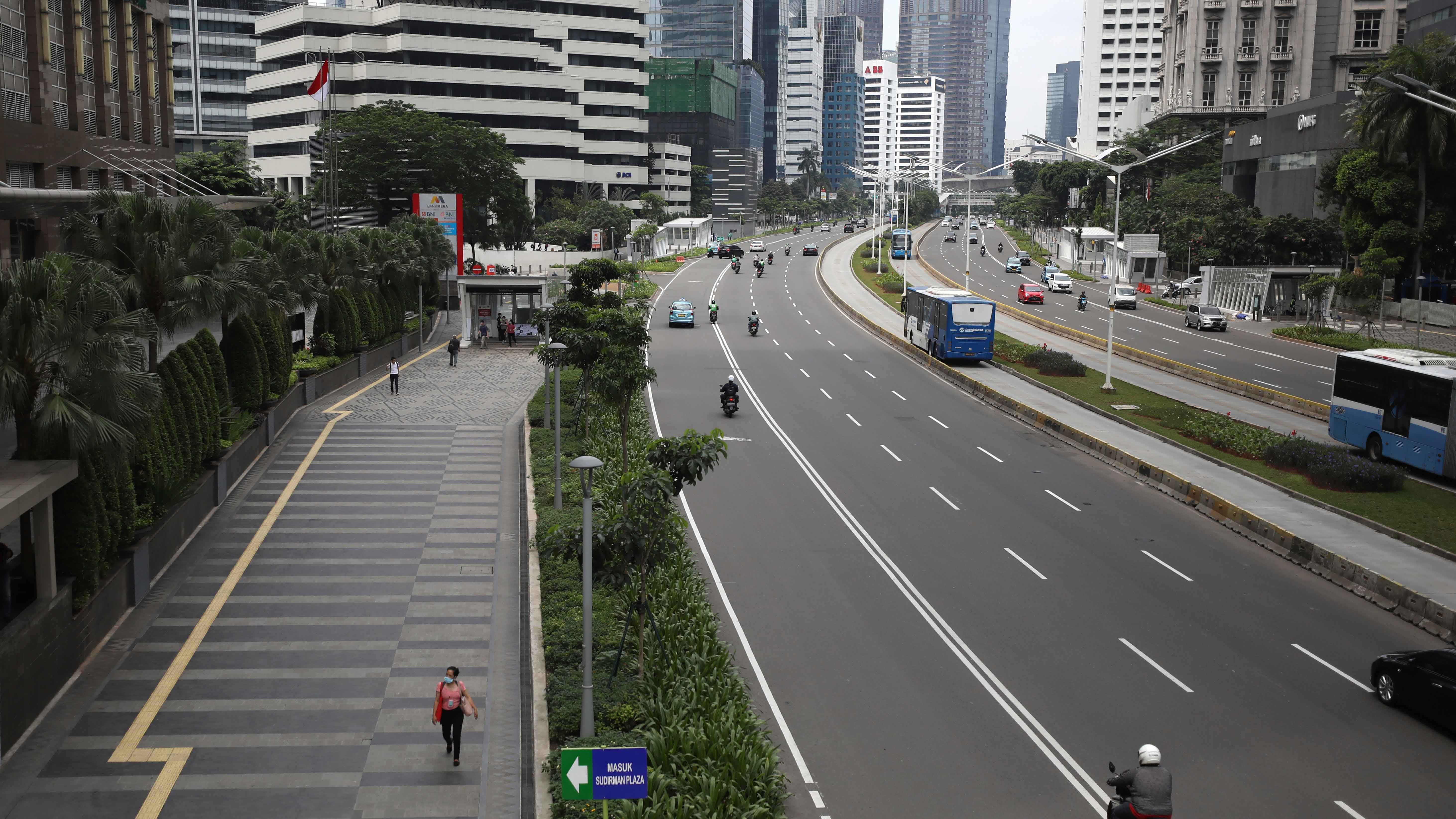 23.03.2020, Indonesien, Jakarta: Eine Frau geht auf dem B&uuml;rgersteig neben einem Abschnitt der normalerweise mit Fahrzeugen verstopften Stra&szlig;e &laquo;Sudirman Street&raquo; im Hauptgesch&auml;ftsviertel von Jakarta, in der aufgrund der Corona-Pandemie nur wenige Fahrzeuge unterwegs sind. Foto: Dita Alangkara/AP/dpa +++ dpa-Bildfunk +++