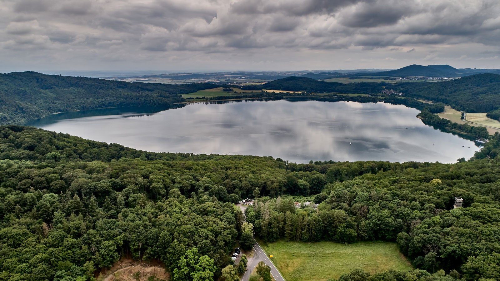 11.06.2020, Rheinland-Pfalz, Wassenach: Der Lacher See, Luftaufnahme mit einer Drohne. Der Eifel-Vulkanismus ist noch aktiv. Forscher haben gemessen, dass sich die Erde dort hebt und auch von unten nach au?en gedr?ckt wird. Die Gefahr eines baldigen Ausbruchs sehen Experten aber nicht. (Zu dpa "Neue Studie belegt: Unter der Eifel brodelt es noch") Foto: Thomas Frey/dpa +++ dpa-Bildfunk +++