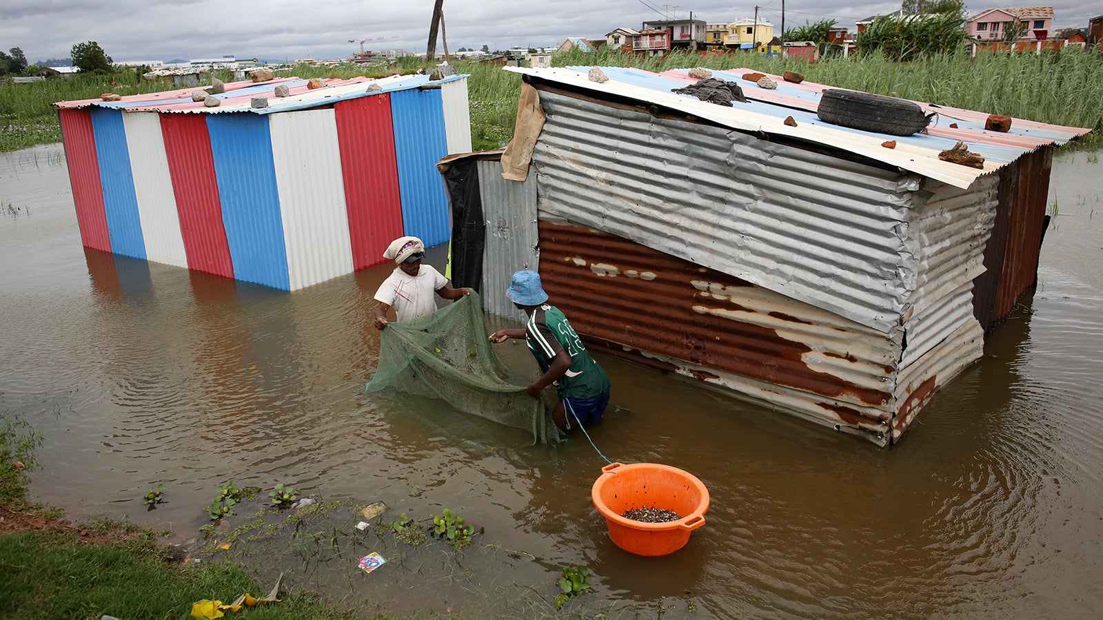 People use a net to catch fish around their flooded dwelling in Antananarivo, Madagascar, Monday, Jan. 24, 2022. Tropical storm Ana has caused widespread flooding in Madagascar, causing the deaths of 34 people and displacing more than 55,000, officials said Monday. With heavy rains continuing, rivers in Antananarivo are rising and officials are urging residents to leave low-lying areas of the capital city and surrounding areas. (AP Photo/Alexander Joe)