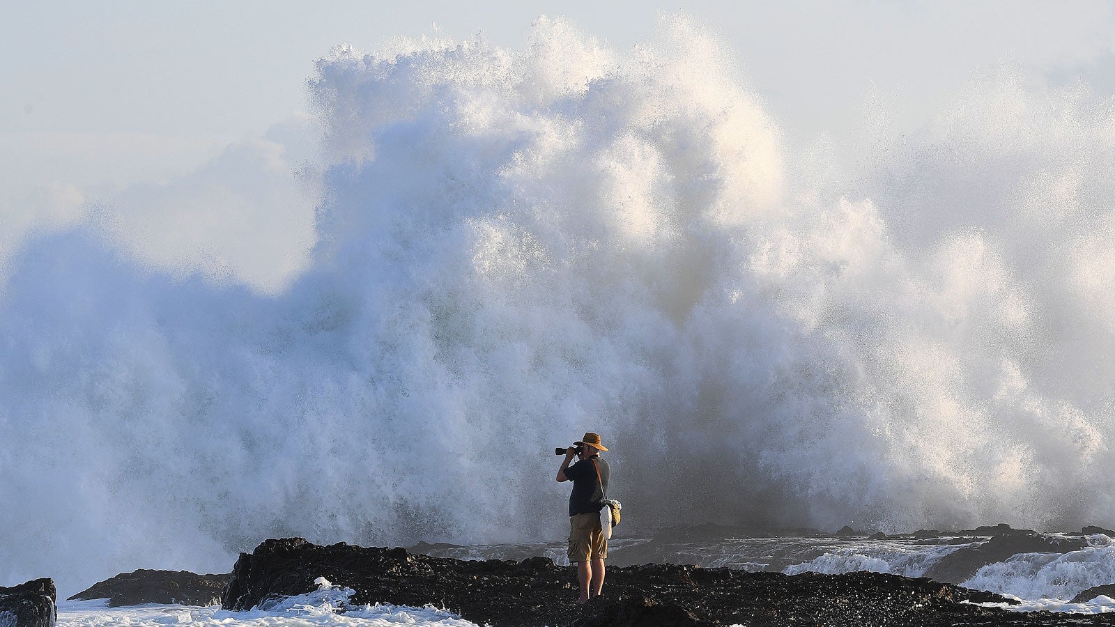 Australien, Queensland, Gold Coast: Ein Fotograf wartet nahe den Snapper Rocks vor der Brandung auf den richtigen Augenblick. Die gro&szlig;en Wellen des Pazifik an der Ostk&uuml;ste sind auch ein Ergebnis des Tropen-Sturms Gita, der vor wenigen Tagen auf den Inseln von Tonga Zerst&ouml;rungen anrichtete. Foto: Dave Hunt/AAP/dpa 
