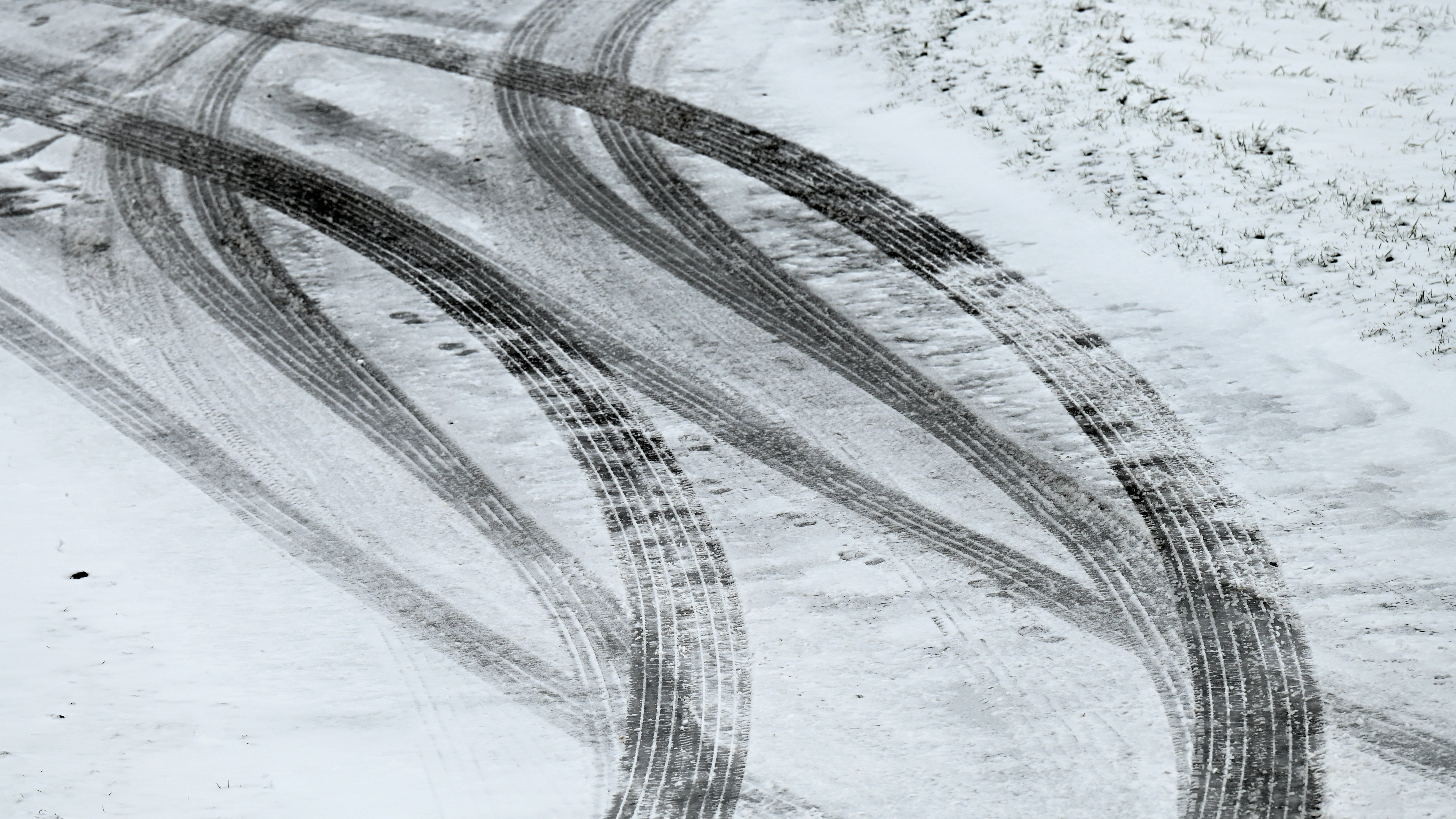 Reifenspuren zeichnen sich auf dem schneebedeckten Asphalt ab. Am Wochenende wird es vielerorts winterlich (Symbolbild) (Uwe Zucchi/dpa)

