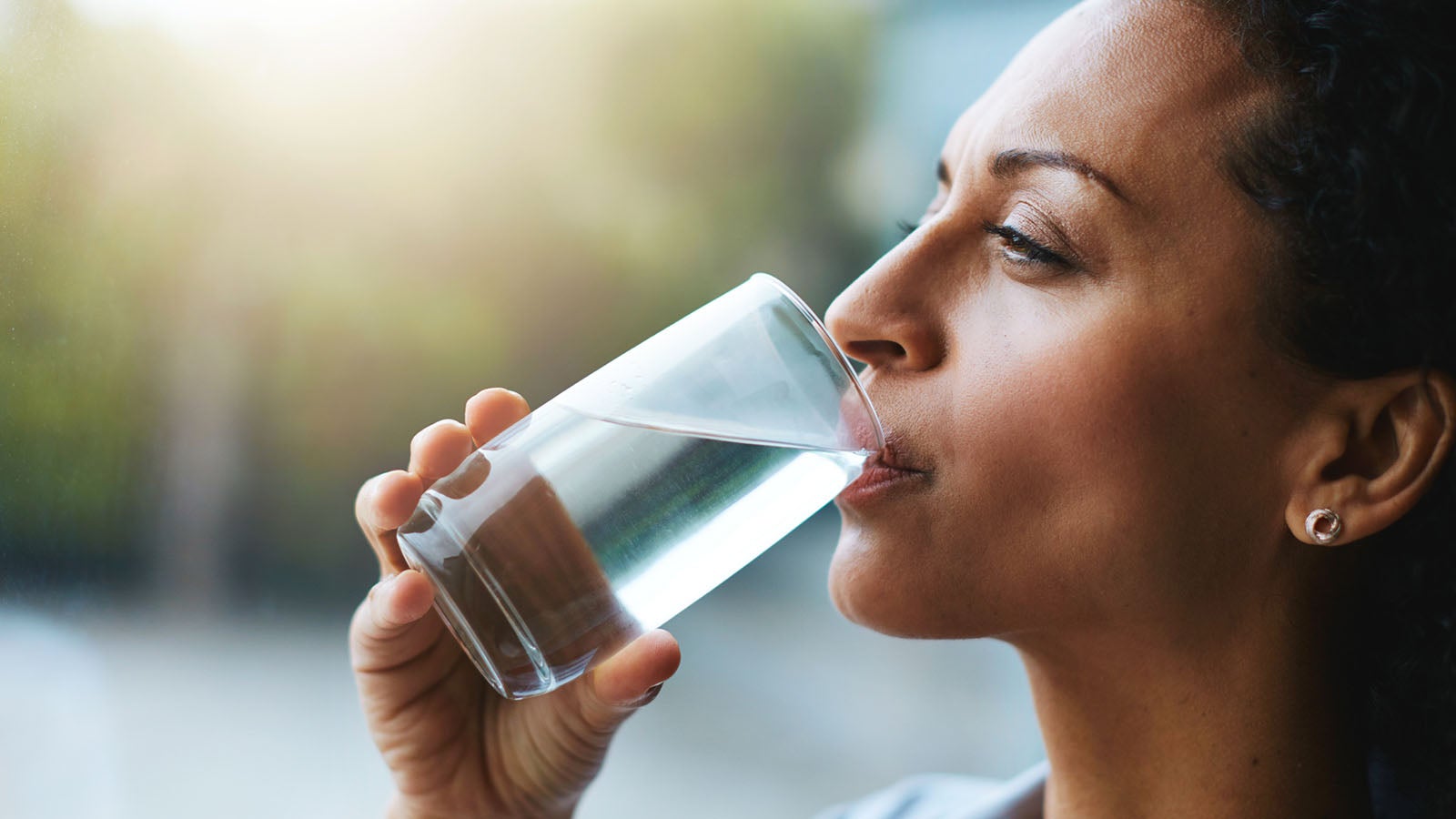 Shot of a woman drinking a glass of water at home