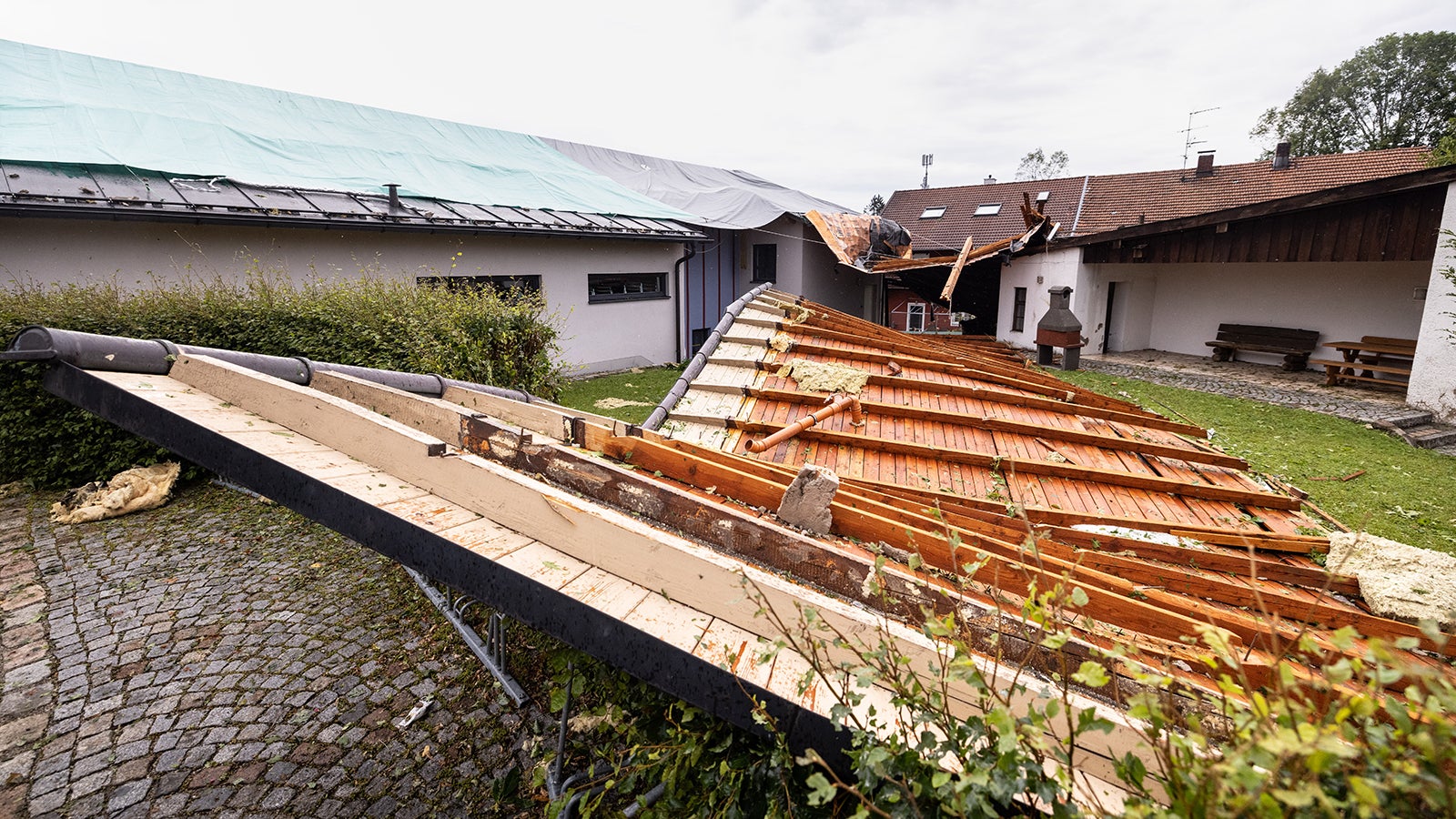 28.07.2021, Bayern, Halfing: Das Dach des Pfarrheims liegt neben dem Geb&auml;ude. Ein heftiges Unwetter ist kurz zuvor &uuml;ber die Region gezogen. Foto: Matthias Balk/dpa +++ dpa-Bildfunk +++