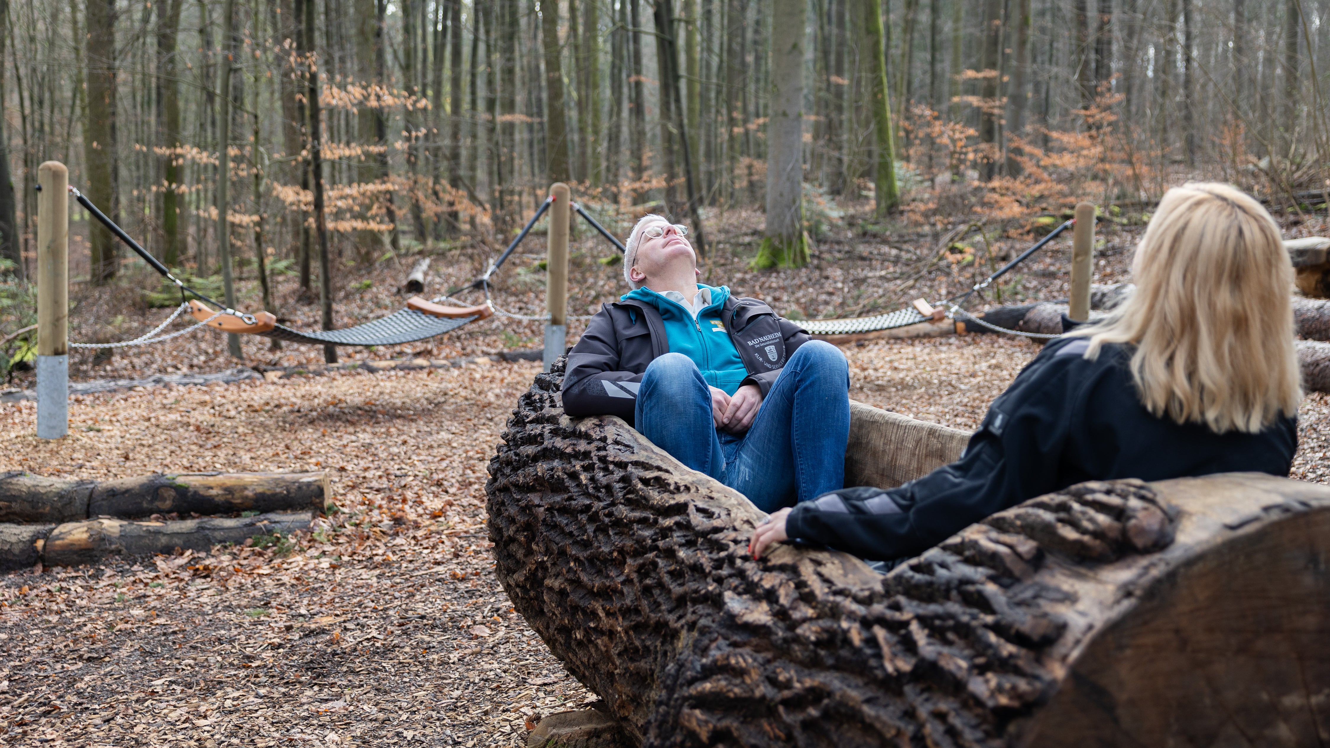 Hessen, Bad Nauheim: Steffen Schneider, Leiter des Kurbetrieb Bad Nauheim, und Anna Redmann, Projektleiterin Heilwald, sitzen in der "Waldbadewanne" im Heilwald Bad Nauheim. In Bad Nauheim befindet sich der erste zertifizierte Heilwald in Hessen. (Lando Hass/dpa)
