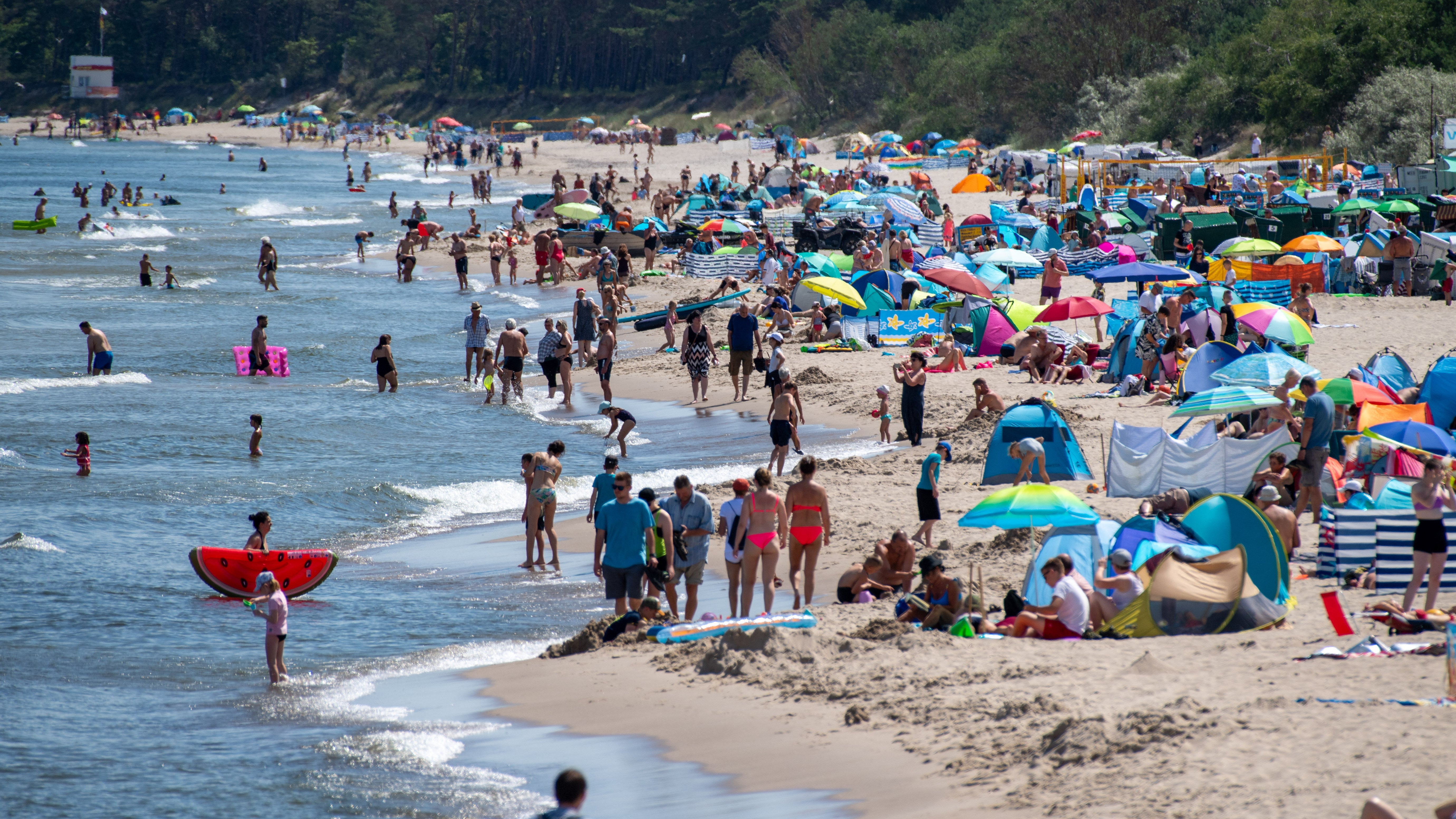 16.07.2023, Mecklenburg-Vorpommern, Zinnowitz: Zahlreiche Menschen sind bei sonnigem Wetter am Strand der Insel Usedom unterwegs. In den meisten Regionen gibt es heute einen Sonne-Wolken-Mix. Nur im S&uuml;dosten und an der K&uuml;ste ziehen einzelne Schauer und zum Teil kr&auml;ftige Gewitter durch. Foto: Stefan Sauer/dpa +++ dpa-Bildfunk +++