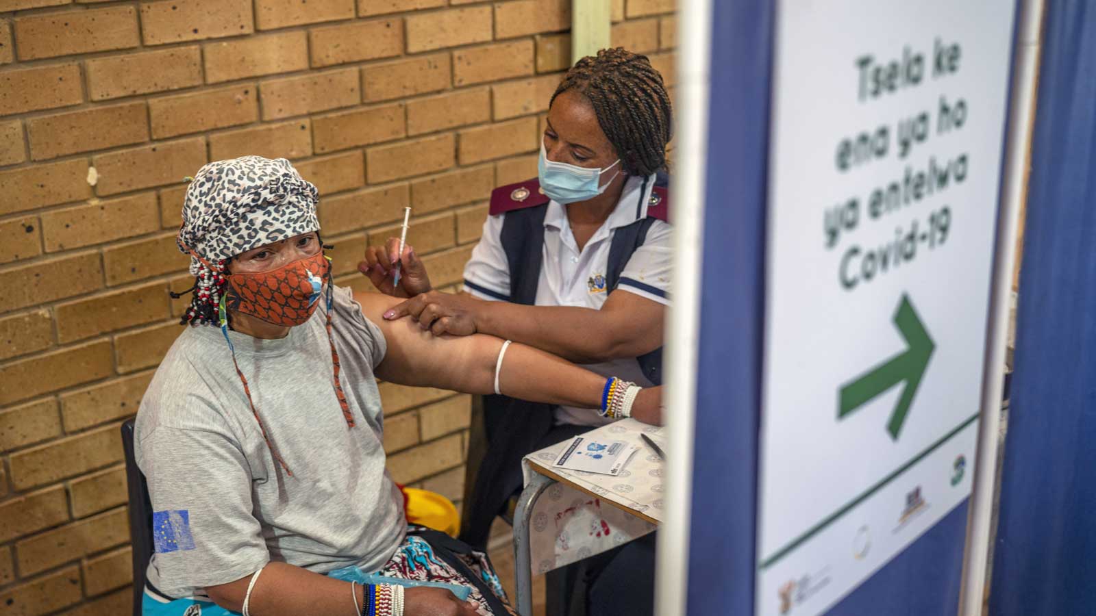 03.12.2021, S&uuml;dafrika, Orange Farm: Eine Frau erh&auml;lt im Mehrzweckzentrum von Orange Farm eine Corona-Impfung. S&uuml;dafrika hat seine Impfkampagne eine Woche nach der Entdeckung der Omikron-Variante des Coronavirus beschleunigt. Die neue Coronavirus-Variante Omikron &uuml;berrascht Wissenschaftler in S&uuml;dafrika durch eine zunehmende Infektion auch von jungen Kindern. Foto: Jerome Delay/AP/dpa +++ dpa-Bildfunk +++