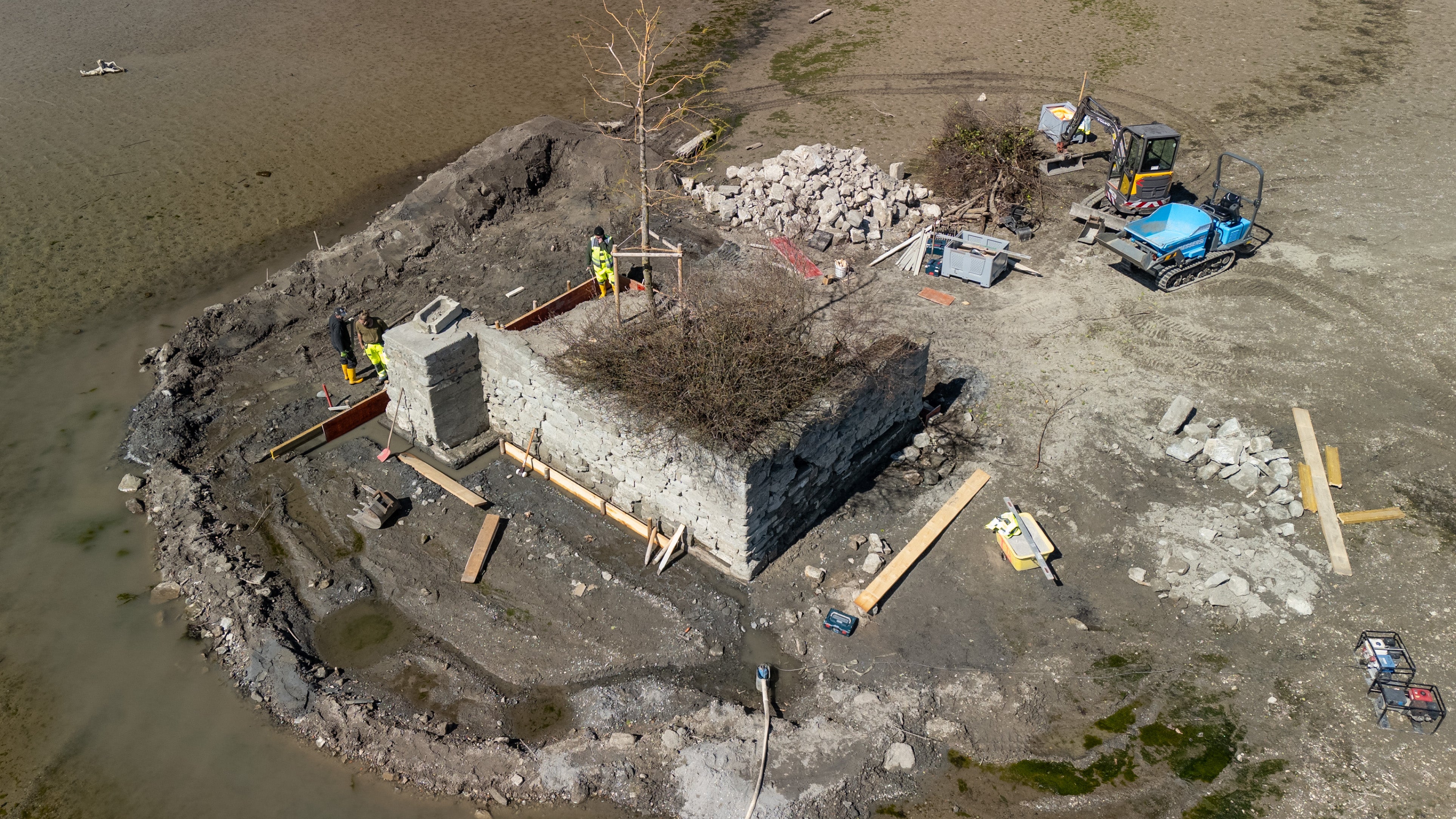 02.04.2025, Bayern, Lindau: Bauarbeiter sanieren eine alte Mauer um die Insel Hoy. Hoy ist mit 53 Quadratmetern die kleinste Insel im Bodensee und normalerweise vom Wasser umsp&uuml;lt. Wegen des aktuell sehr niedrigen Wasserstands, k&ouml;nnen Baumaschinen trocken bis dort hinfahren. (Aufnahme mit Drohne) (Florian Bodenm&uuml;ller/swd-medien/dpa)