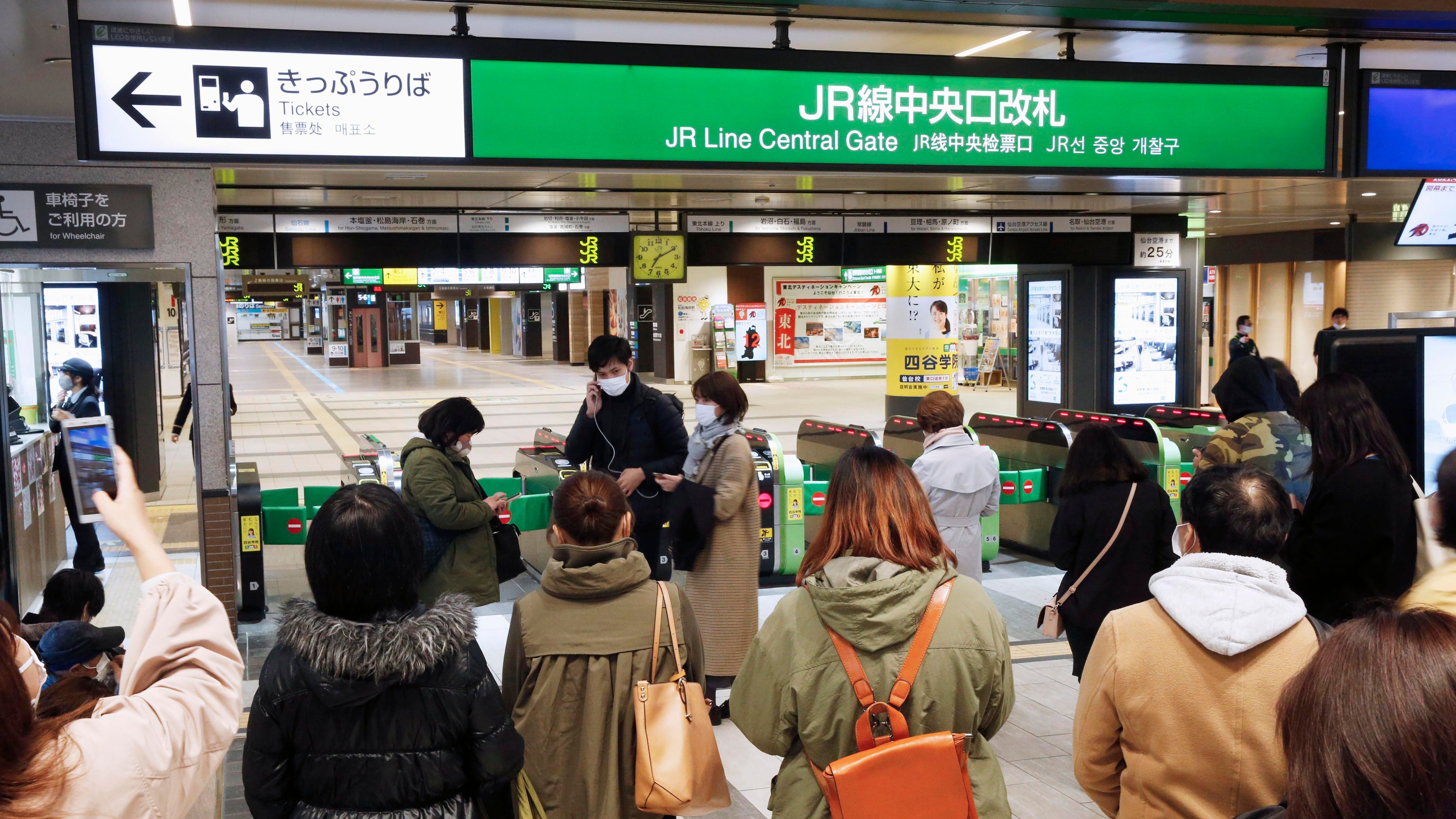 Menschen stehen vor einem Fahrkartenschalter an einem Bahnhof, w&auml;hrend der Zugverkehr nach einem Erdbeben eingestellt wurde. 