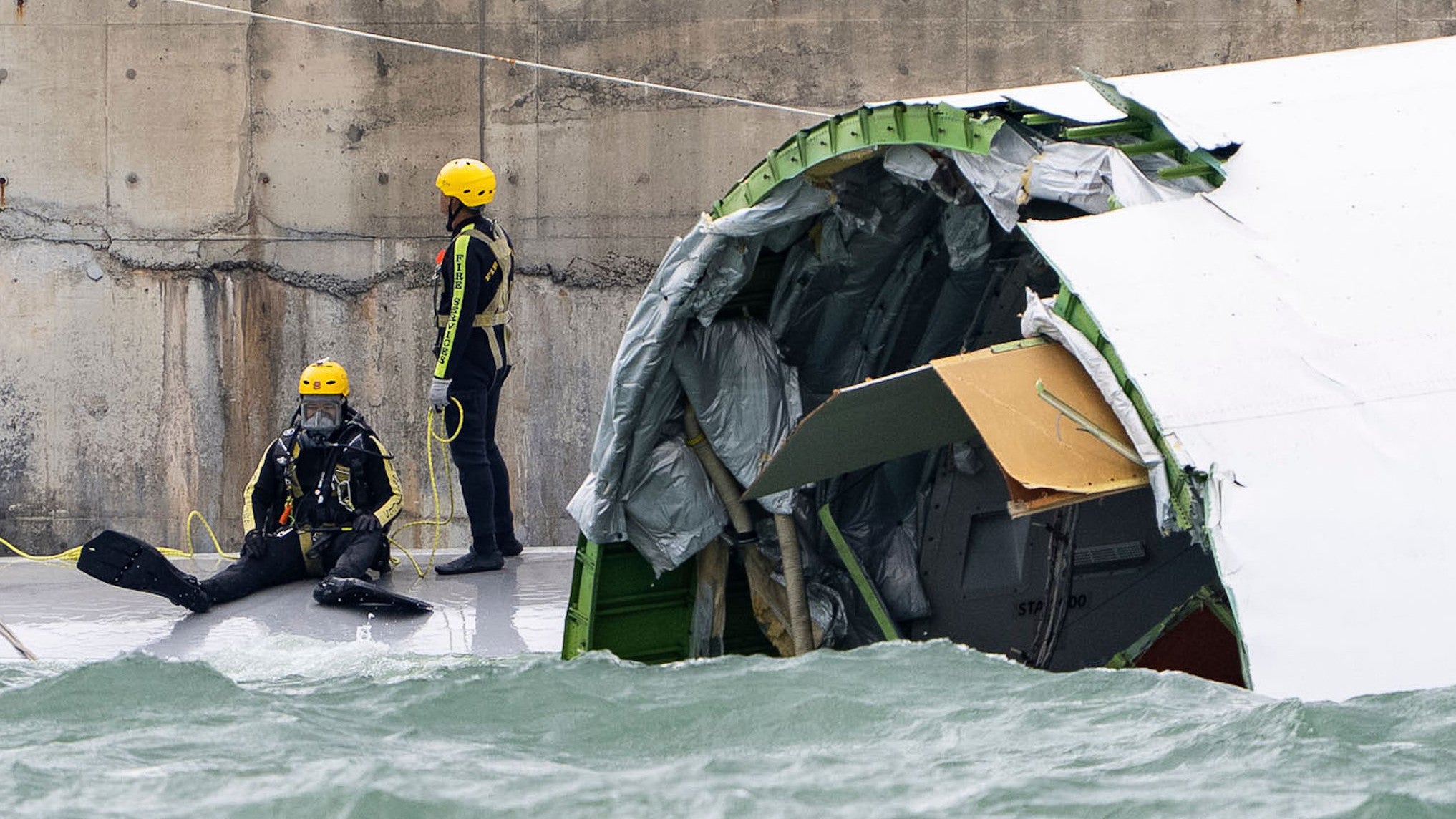 20.10.2025, Hongkong: Ein Taucher bereitet sich auf die Inspektion des Frachtflugzeugs vor, das auf dem Flughafen in Hongkong von der Landebahn abgekommen ist und &uuml;ber die Piste hinaus ins Meer schlitterte. Auf dem Flughafen der Millionenmetropole Hongkong ist es zu einem t&ouml;dlichen Flugzeugungl&uuml;ck gekommen. (Chan Long Hei/AP/dpa)

