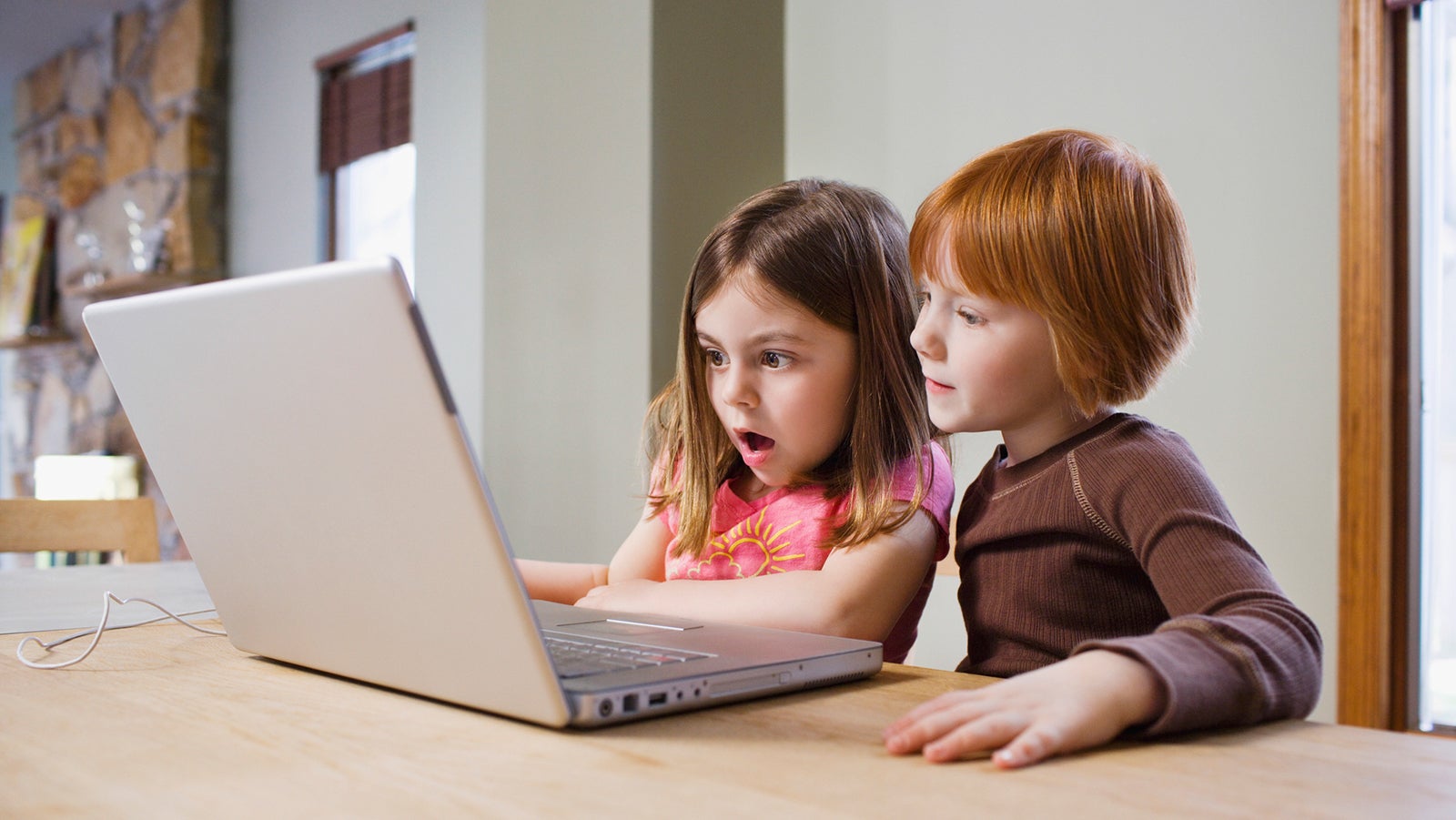 Shocked young girls using laptop at table