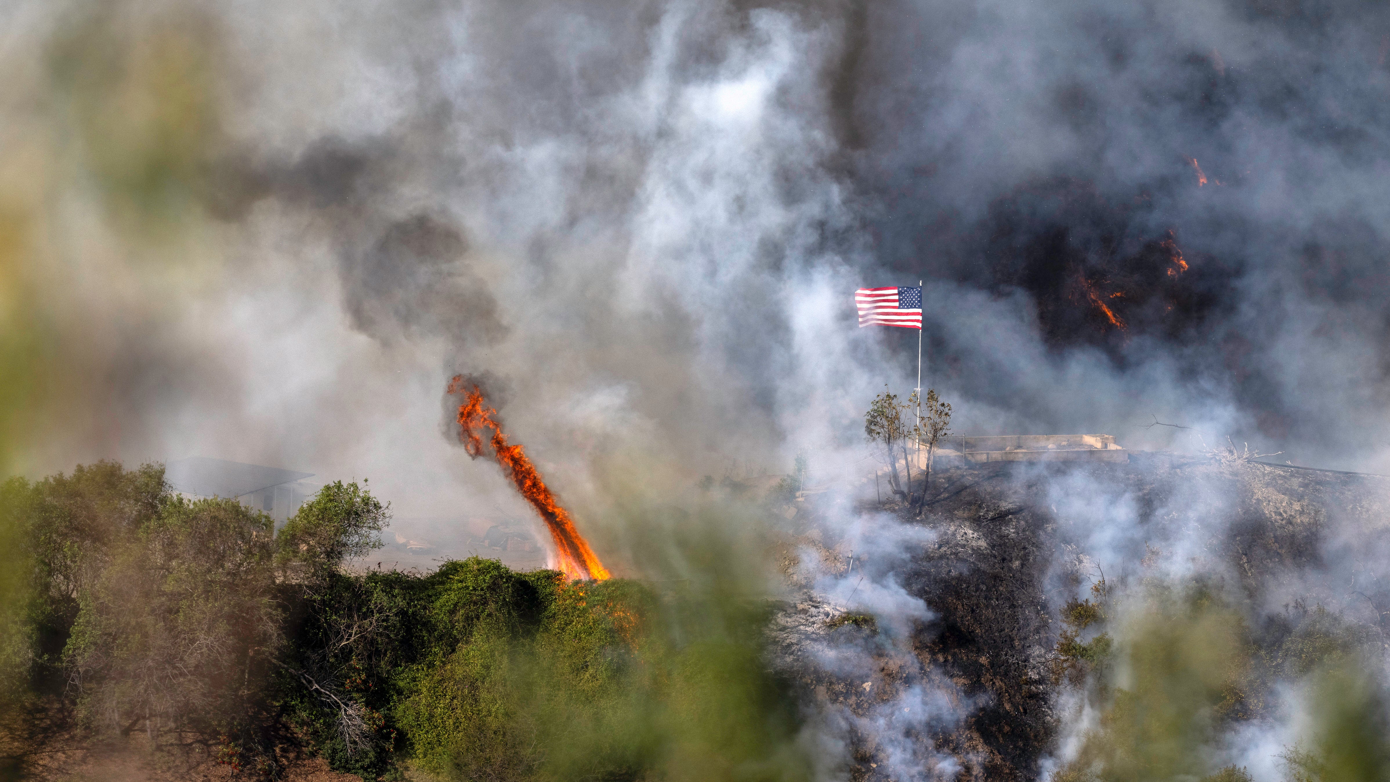 11.01.2025, USA, Los Angeles: Eine amerikanische Flagge weht &uuml;ber einem Teil des Mandeville Canyon, der durch das Palisades-Feuer zerst&ouml;rt wurde. (Mark Edward Harris/ZUMA Press Wire/dpa)
