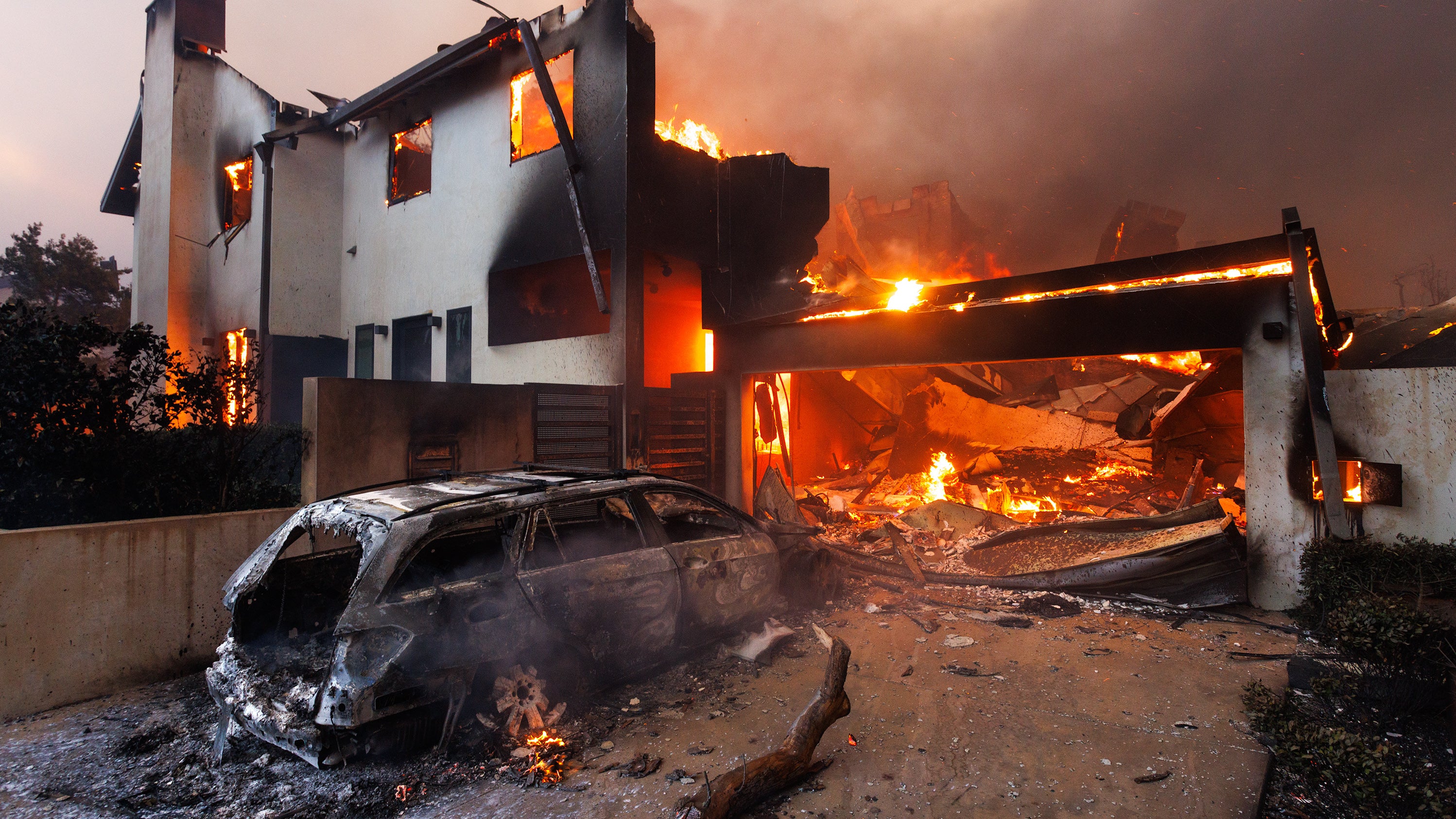 08.01.2025, USA, Los Angeles: Ein verbranntes Auto parkt vor einem abgebrannten Haus in Pacific Palisades w&auml;hrend des zweiten Tages des Palisades-Feuers. (Jonathan Alcorn/ZUMA Press Wire/dpa)
