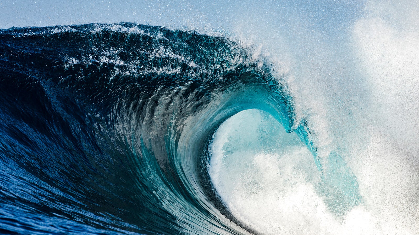 Powerful blue breaking wave breaking in the open ocean on a sunny day